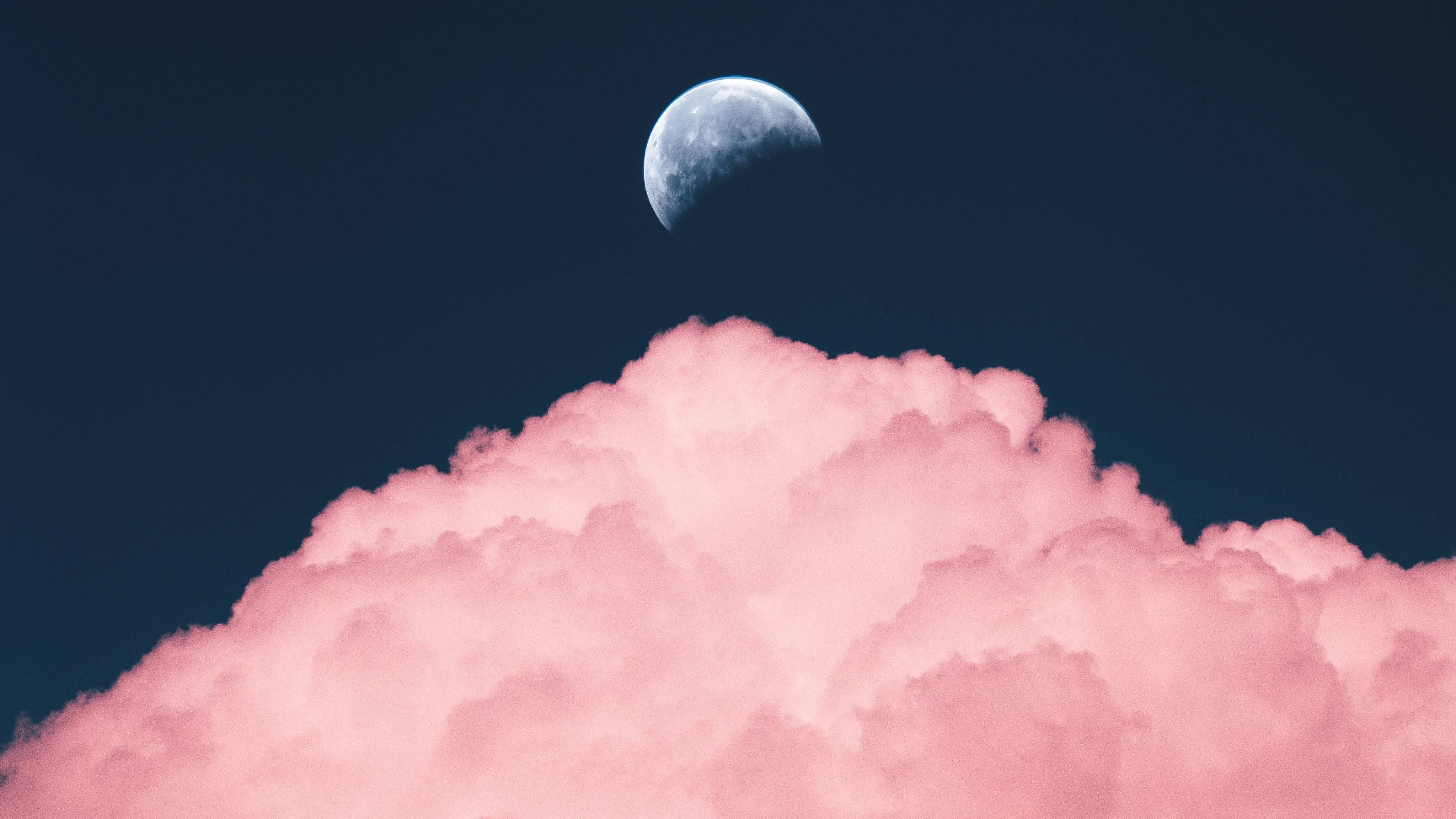 美學 桌布 壁紙 — 一彎新月在深藍色夜空中的一朵蓬鬆粉紅雲朵上方發光。