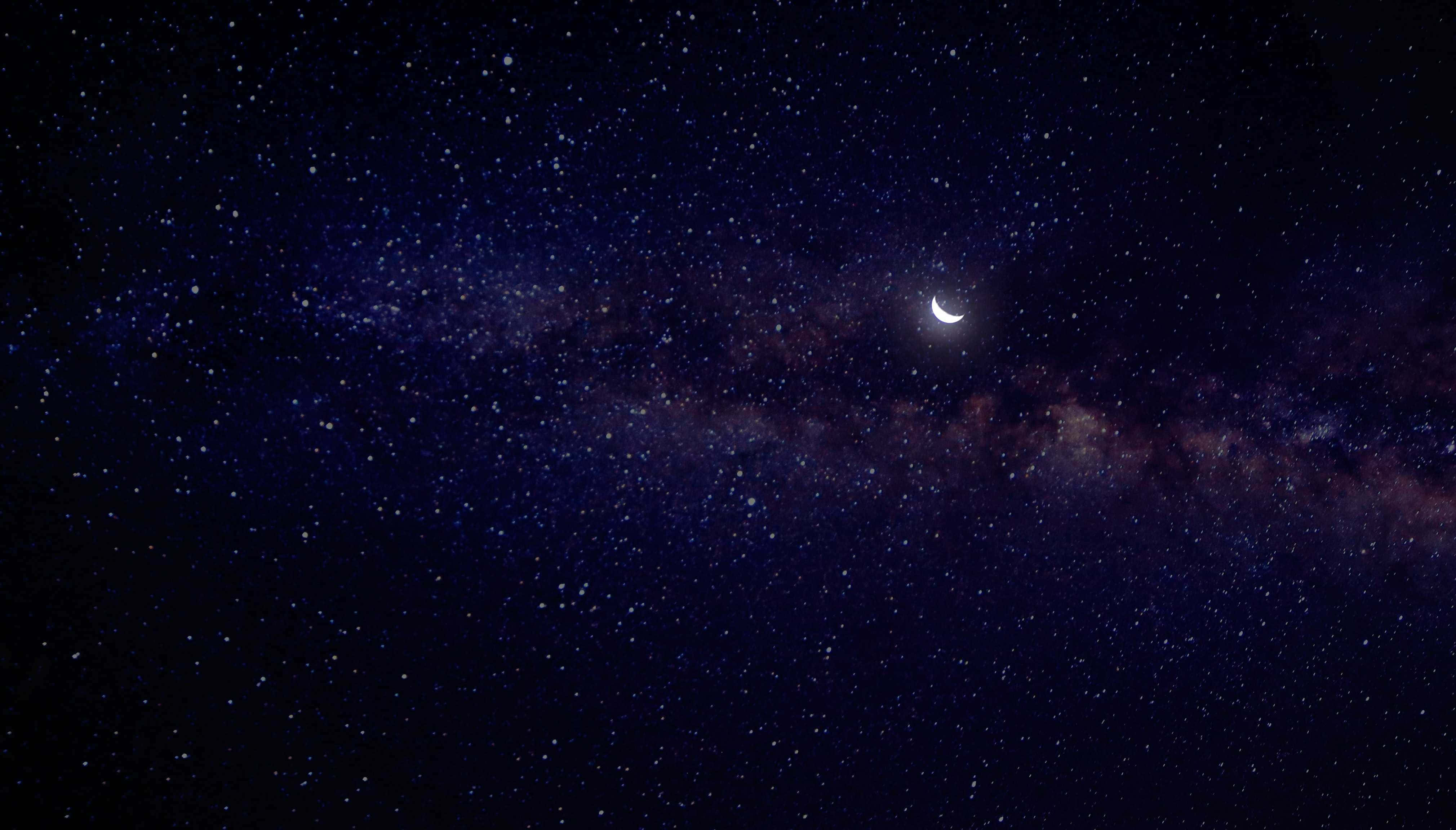 Moon And Stars iPhone 桌布 壁紙 — 一彎新月在深靛藍夜空中的銀河密集星場上方柔和發光。