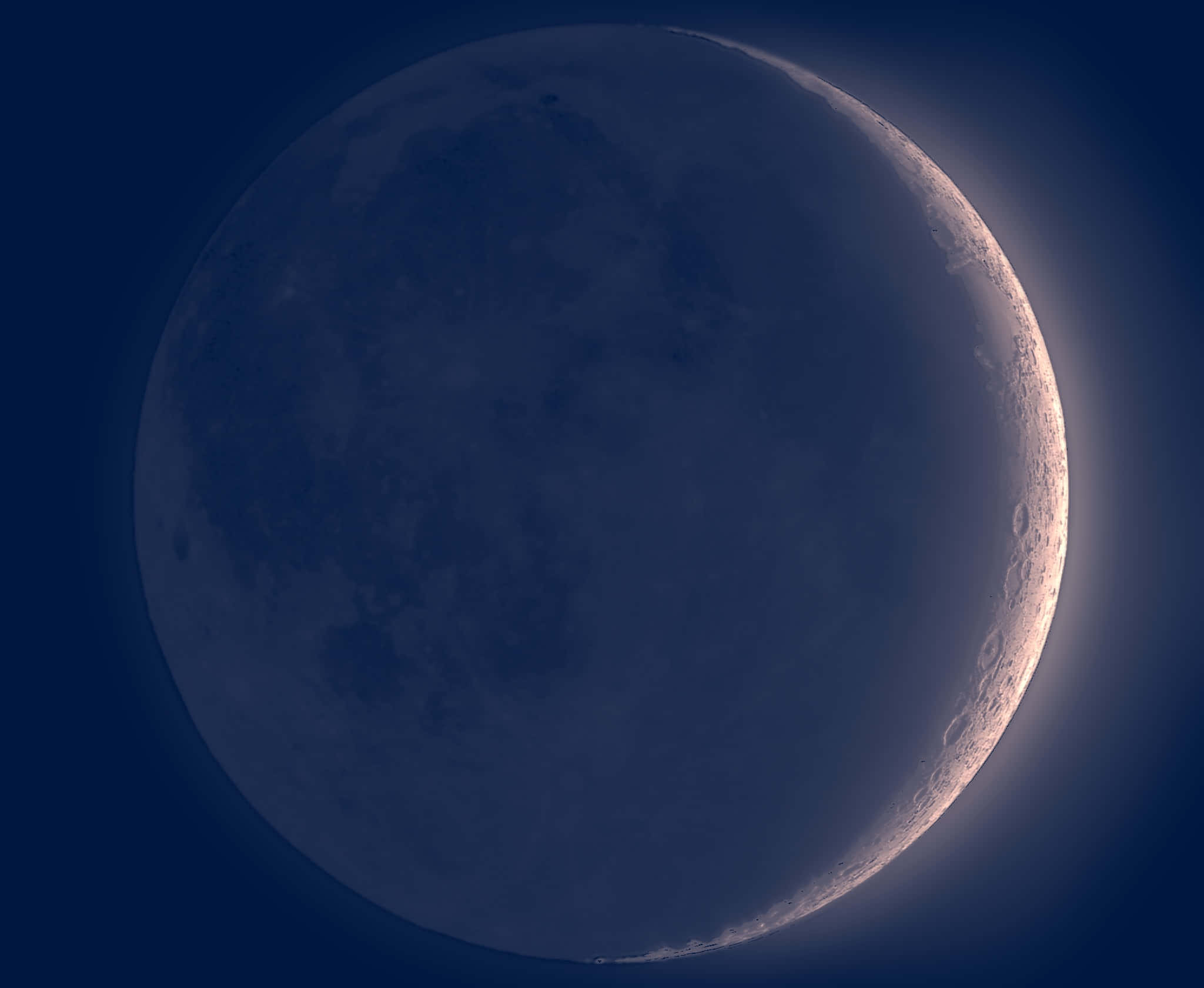 Moonlight 桌布 壁紙 — 一彎新月在深靛藍色的天空中柔和地發光，其照亮邊緣上可見詳細的隕石坑。
