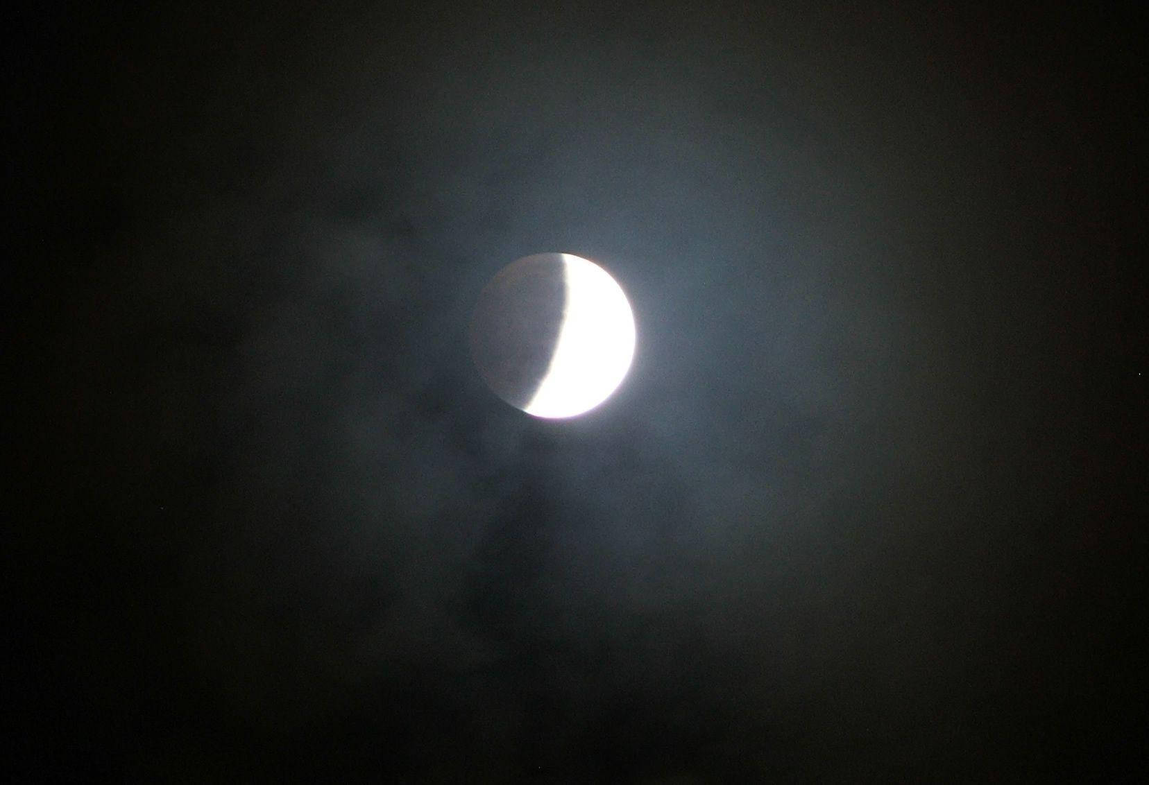 Eclipse 桌布 壁紙 — 一彎新月在黑暗的夜空中透過縷縷雲層明亮地發光。