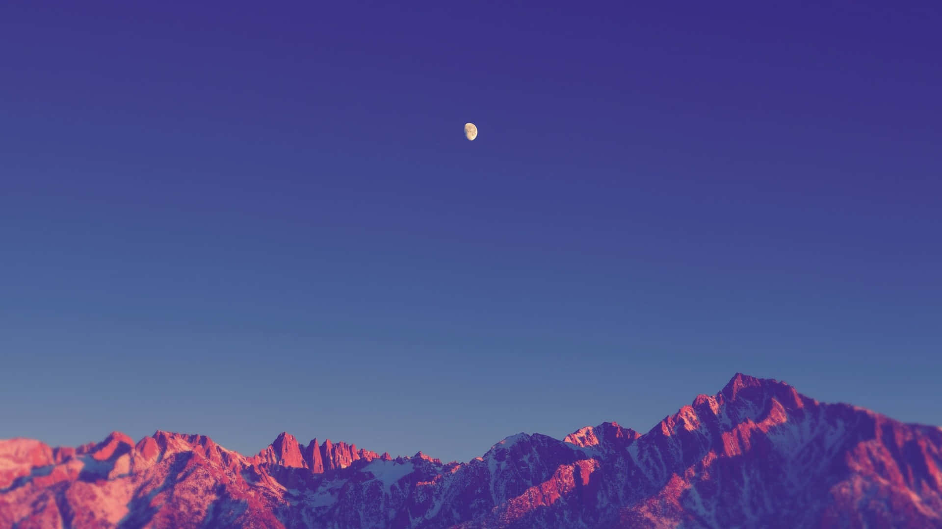 Minimalist Sky 桌布 壁紙 — 一彎新月懸掛在鋸齒狀的雪山之上，沐浴在粉紅和紫色的暮色之中。