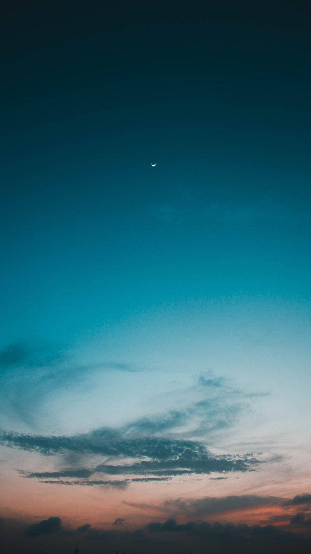Sunset Aesthetic 桌布 壁紙 — 一彎新月掛在從深藍色過渡到柔和粉紅色和橙色雲彩的暮色天空中。