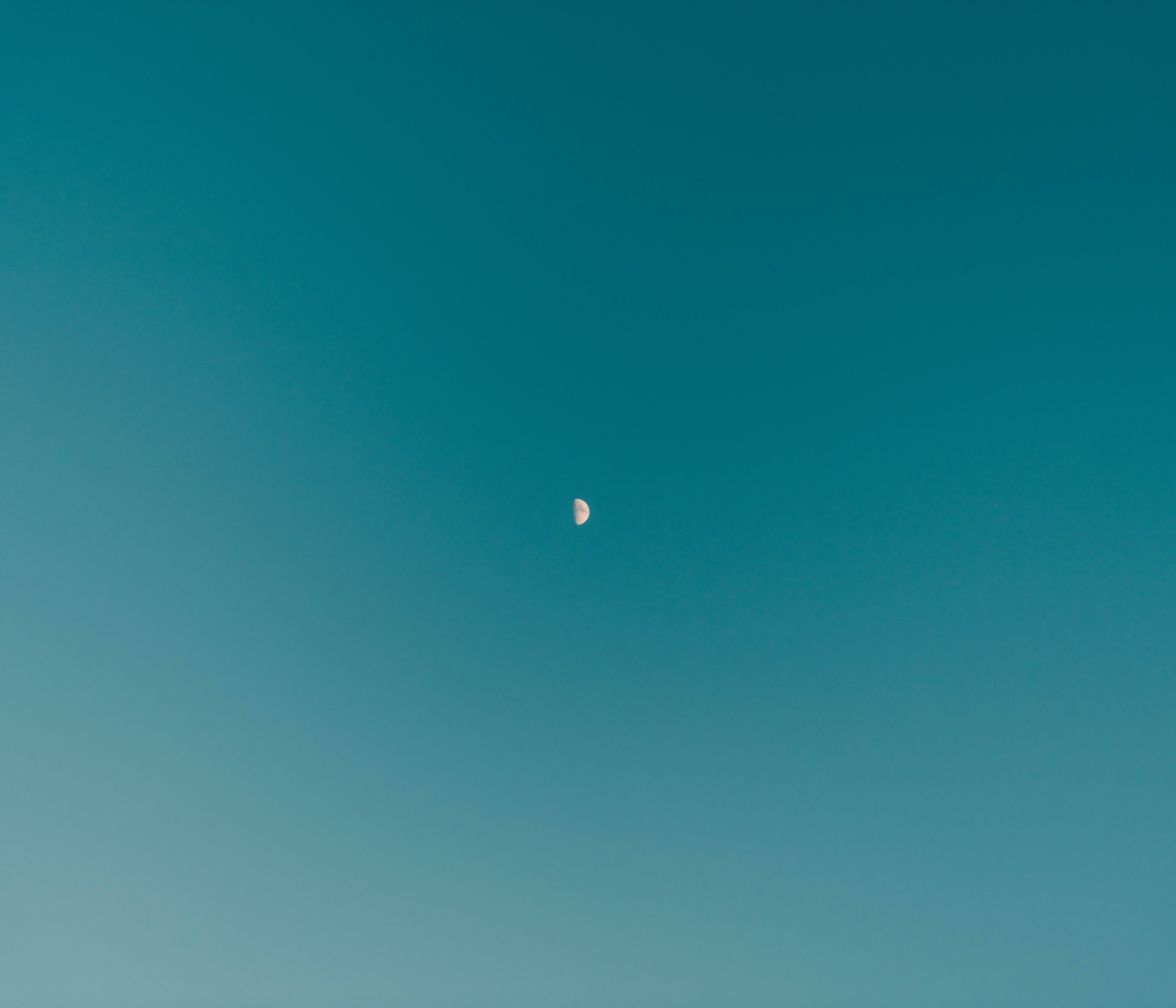青色GIF 桌布 壁紙 — 一彎精緻的月牙在廣闊的漸層青綠色天空中柔和發光。