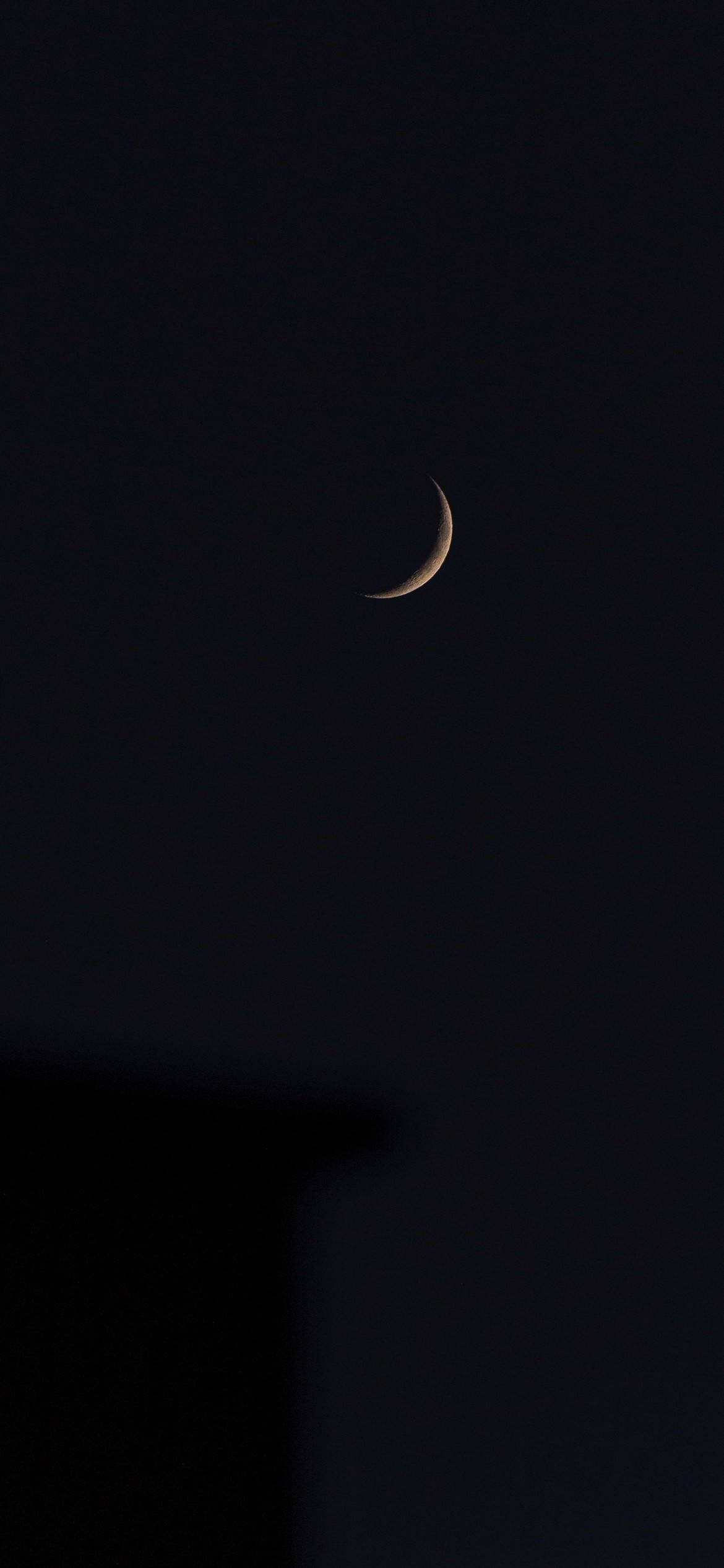 Crescent Moon 桌布 壁紙 — 一彎精緻的月牙在深邃的黑色夜空中柔和發光，下方有模糊的建築物剪影。