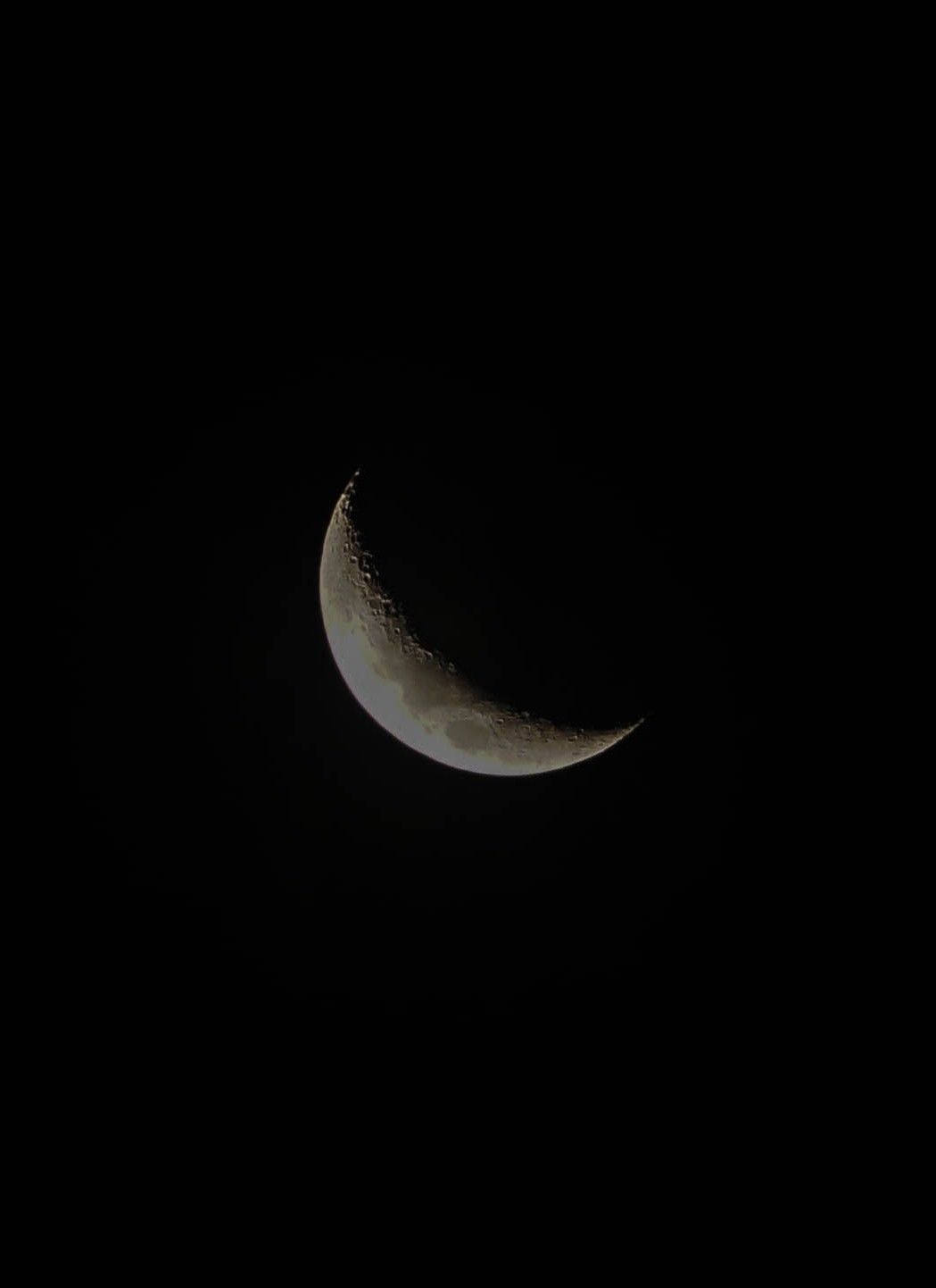 月光 桌布 壁紙 — 一彎精緻的月牙在漆黑的夜空中柔和地發光，顯露出隕石坑和月球地形。