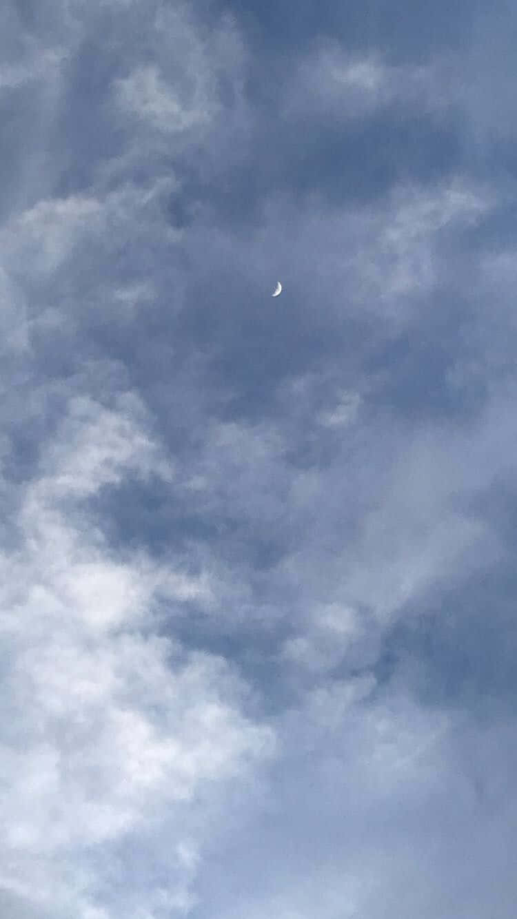 雲朵 桌布 壁紙 — 一彎纖細的月牙在佈滿縷縷藍白雲朵的廣闊天空中柔和地發光。