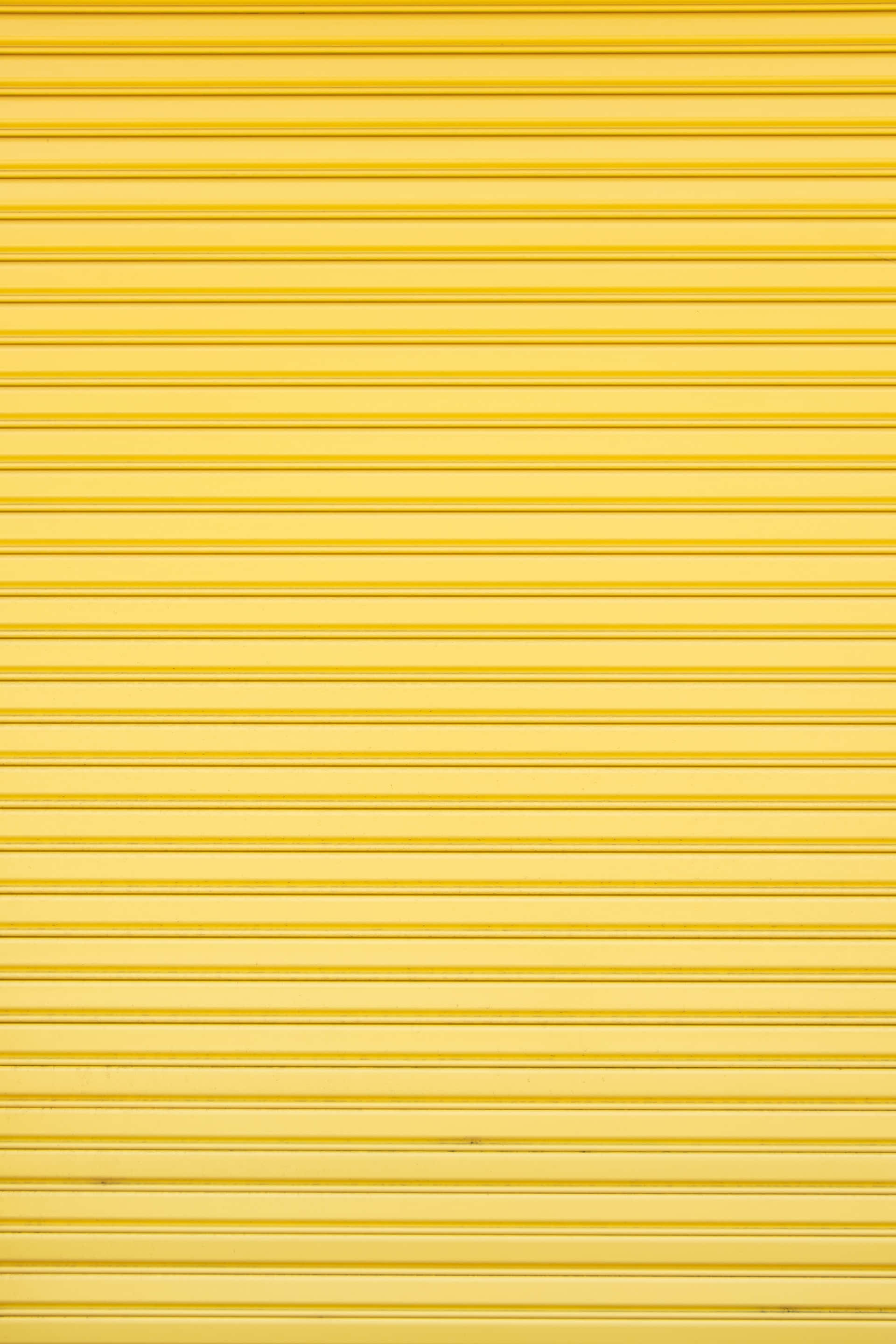 Yellow Pattern 桌布 壁紙 — 一扇亮黃色金屬捲門的特寫，帶有水平條紋和細微陰影。