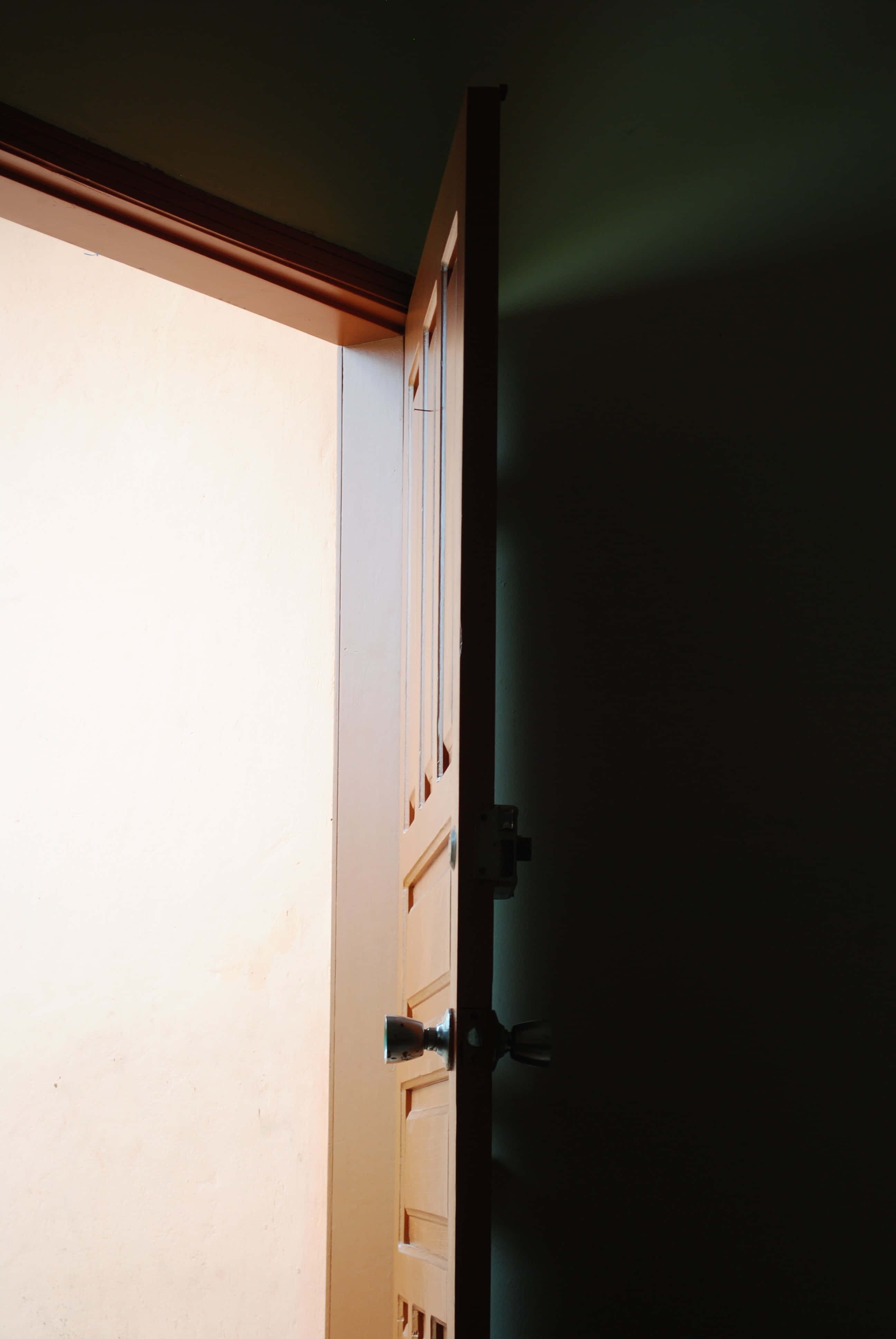 Door 桌布 壁紙 — 一扇半開的木門露出明亮的光線，與深邃陰暗的內部形成對比。