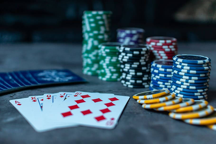 chips 桌布 壁紙 — 一手獲勝的撲克牌：A、K、Q、J、10 方塊，旁邊是色彩繽紛的籌碼堆，放在深色桌子上。