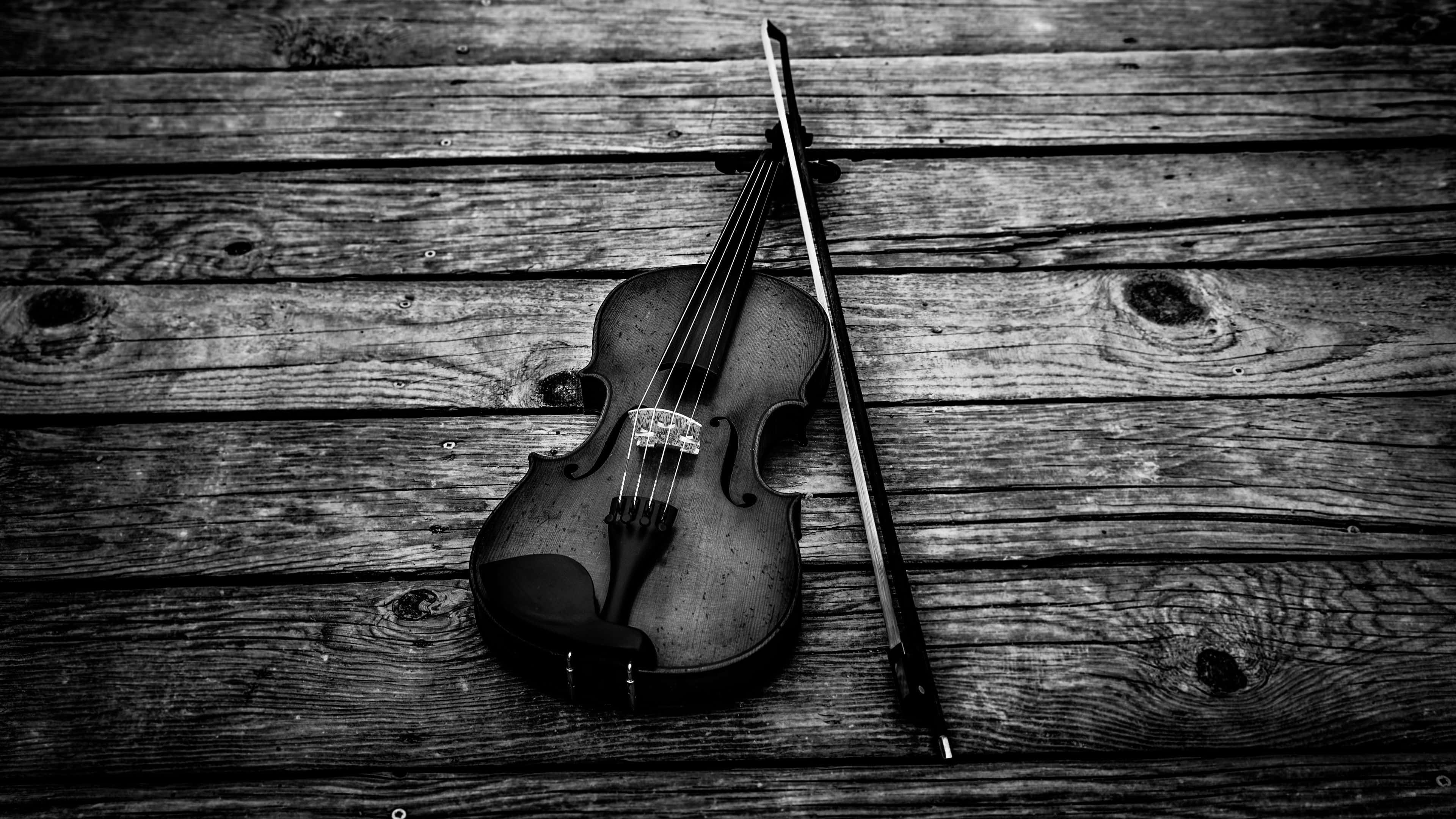 Black And White Music 桌布 壁紙 — 一把單色小提琴和琴弓放在帶有深木紋紋理的風化木板上。