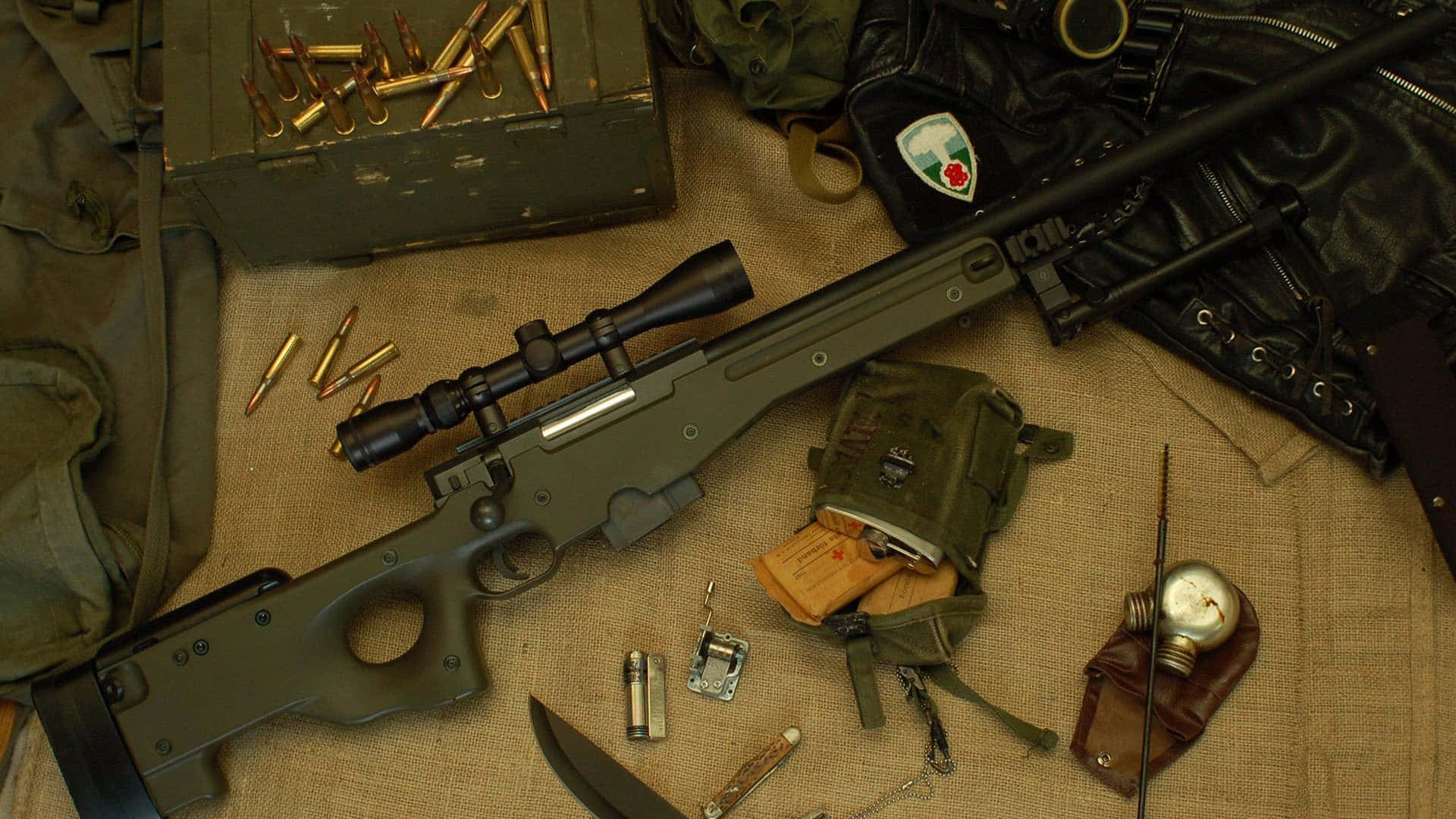 Rifle 桌布 壁紙 — 一把帶有瞄準鏡和彈藥的軍用狙擊步槍放置在麻布表面上，周圍環繞著裝備和一個復古指南針。