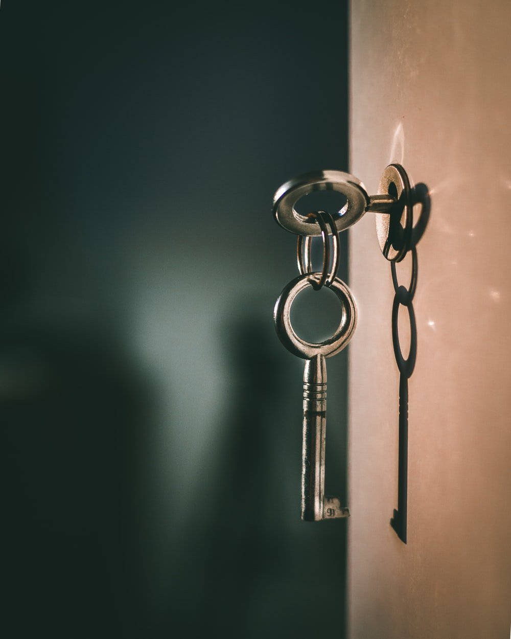 key 桌布 壁紙 — 一把復古金屬鑰匙掛在木門的鏈條上，在溫暖的光線下投射出清晰的陰影。