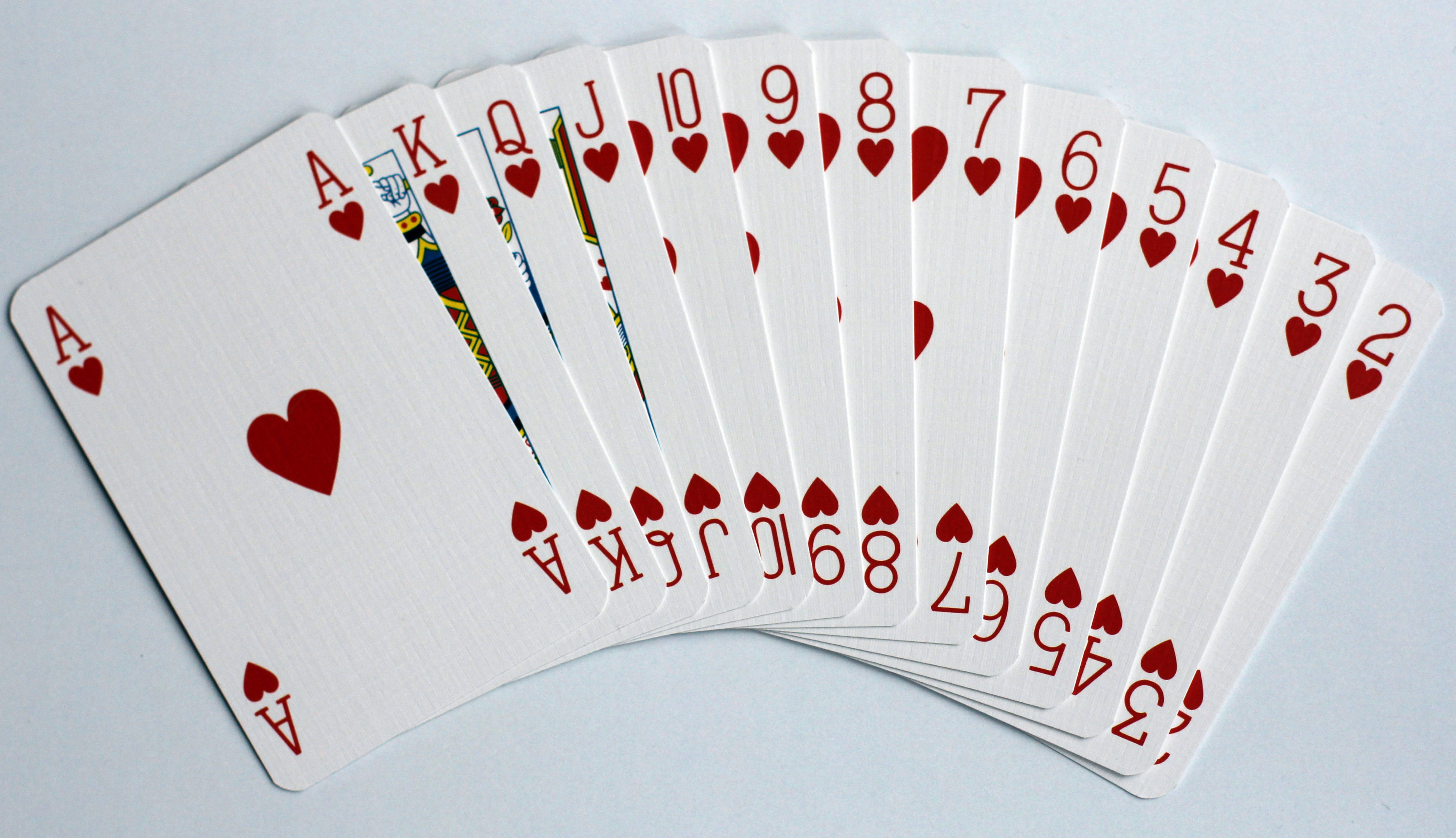 Playing Cards 桌布 壁紙 — 一把撲克牌扇，展示從Ace到2的整個紅心花色，背景為純淺灰色。