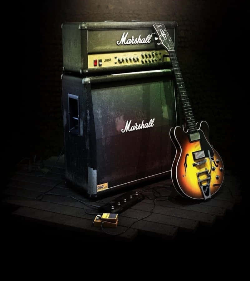 Guitar Amp 桌布 壁紙 — 一把旭日紋電吉他靠在一台復古Marshall音箱旁，身處昏暗錄音室，溫暖的聚光燈照射著。