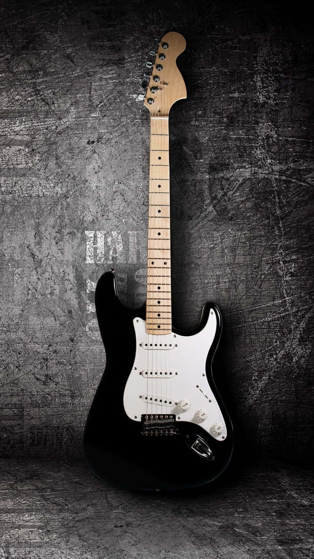 Bass Guitar 桌布 壁紙 — 一把時尚的黑色電吉他，配有白色護板，直立靠在有紋理的深灰色混凝土牆上。
