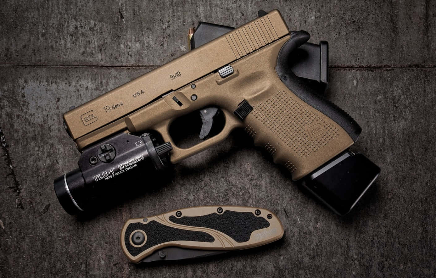 Glock 19 桌布 壁紙 — 一把棕褐色Glock 19 Gen4手槍連同雷射瞄準器和相配的折疊刀放置在風化的混凝土表面上。