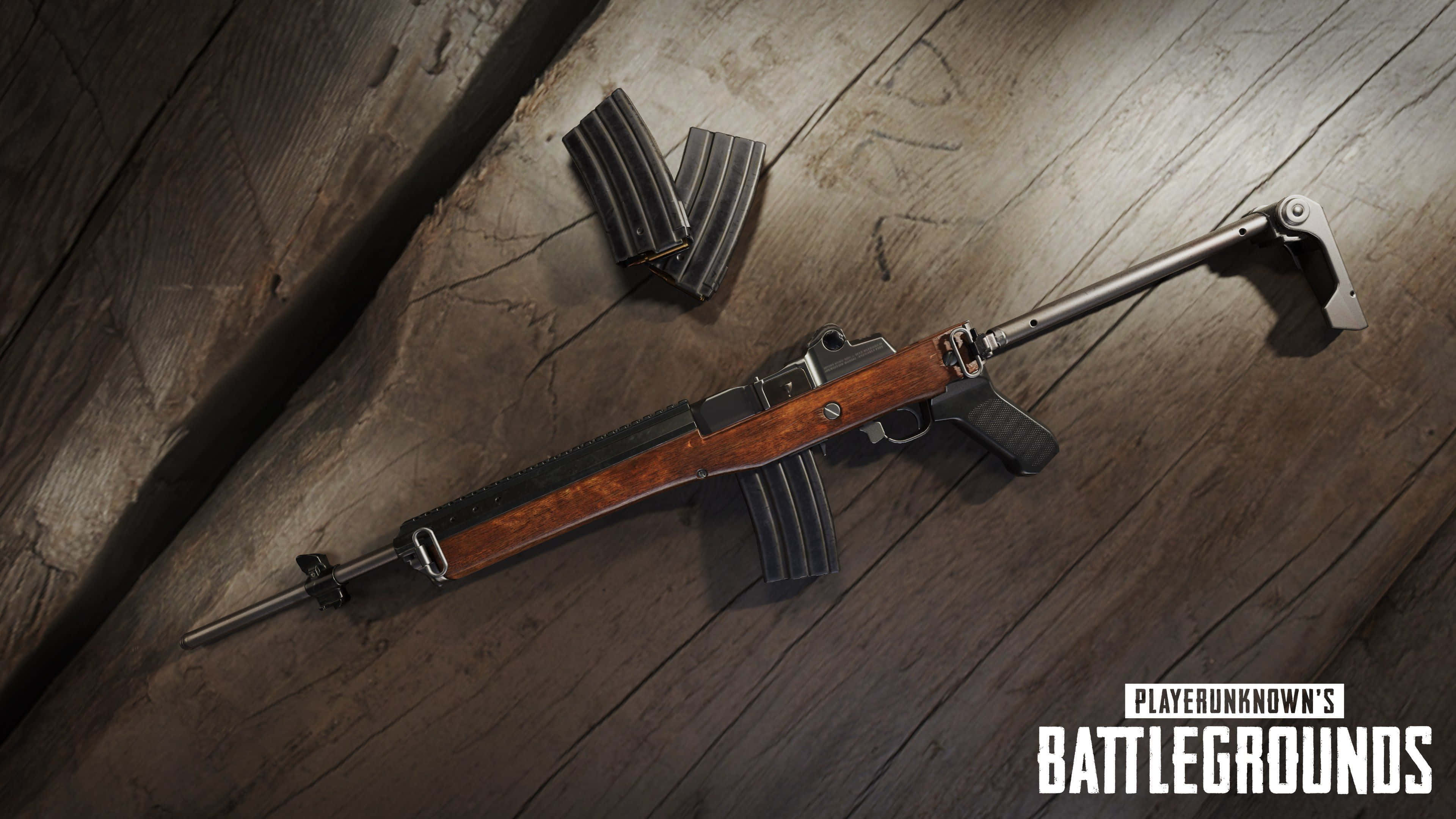 Pubg Guns 桌布 壁紙 — 一把細節豐富的突擊步槍，配有木製槍托和金屬彈匣，放置在風化的木板上，遊戲標誌清晰可見。