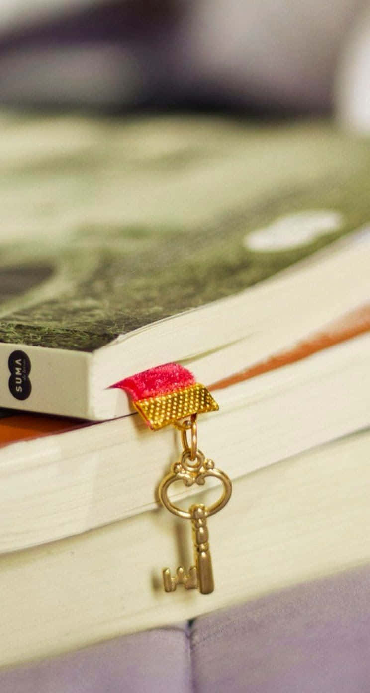 桌布 壁紙 — 一把金色鑰匙連紅色絲帶書籤掛在木質表面上名為「SUMA」的書本邊緣。