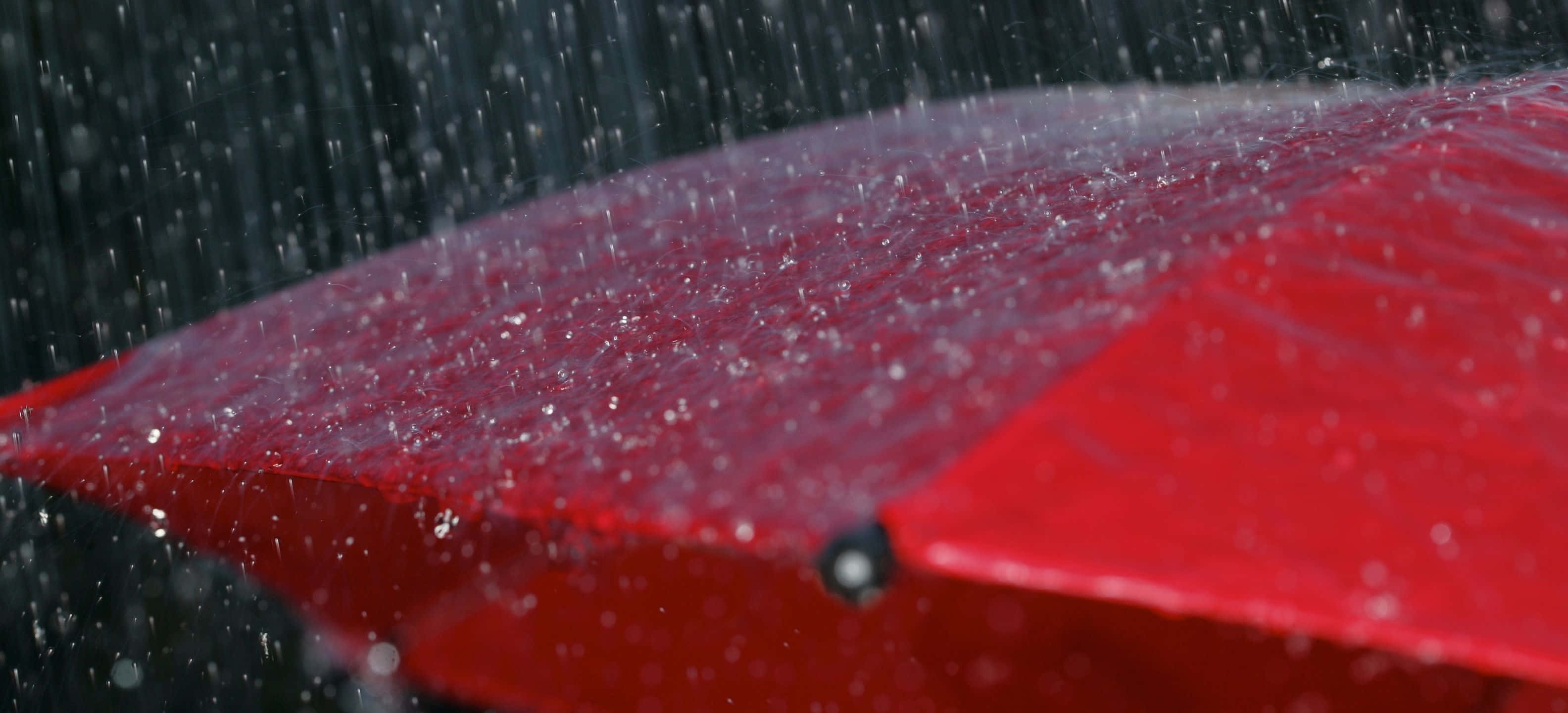 3168x1440 桌布 壁紙 — 一把鮮紅色的雨傘抵擋著大雨，表面上的水滴閃閃發光。