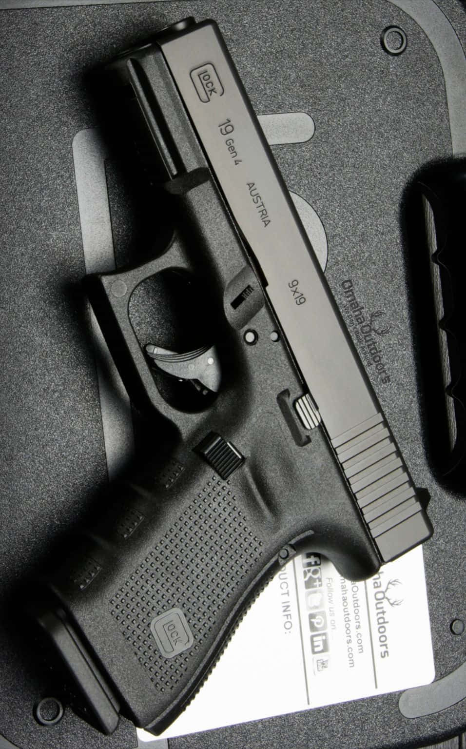 槍枝 桌布 壁紙 — 一把黑色Glock 19 Gen 4手槍放置在帶紋理的灰色收納盒中，下方有一張白色產品卡。