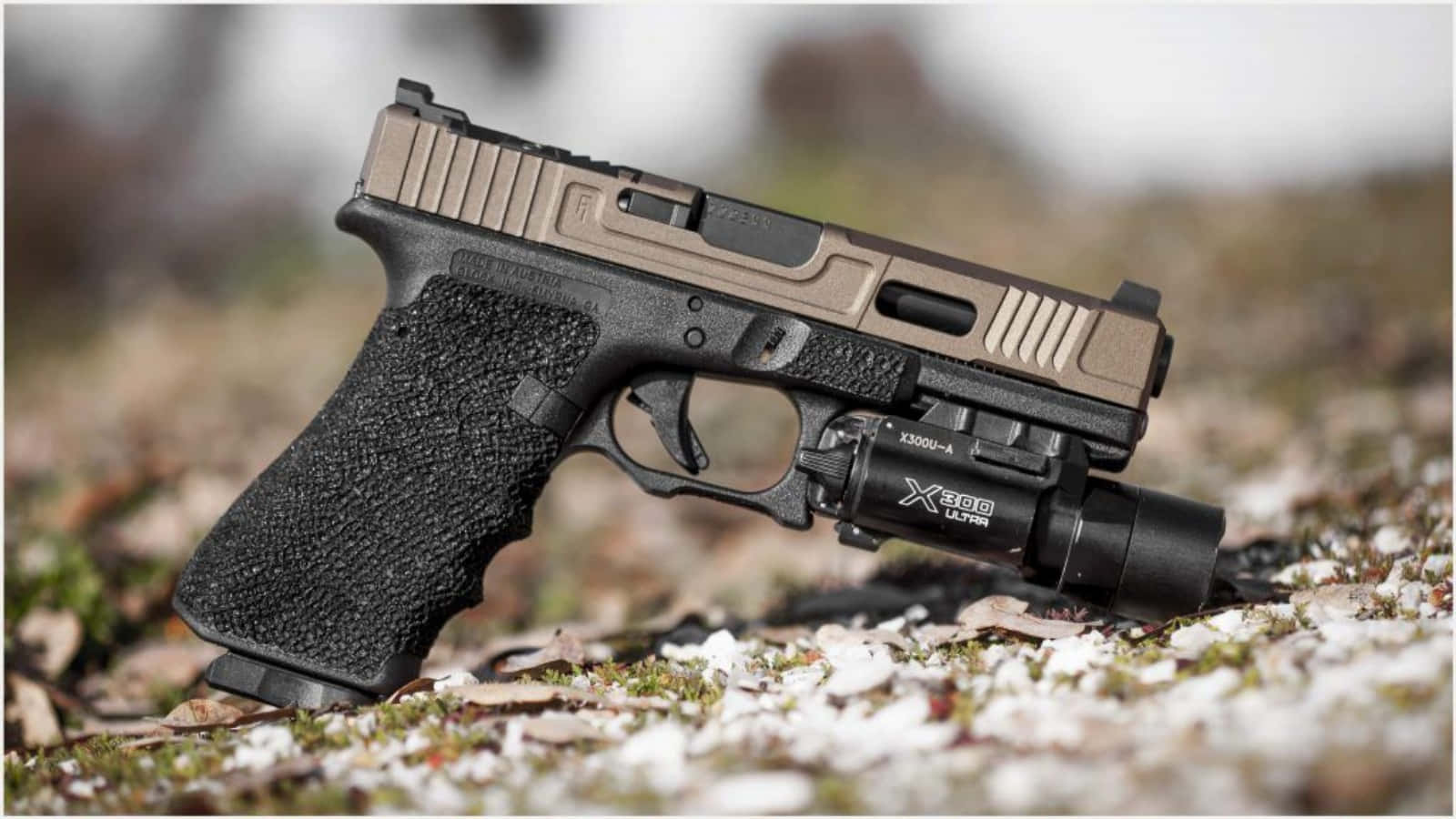 Glock 19 桌布 壁紙 — 一把黑色和棕褐色半自動手槍配有戰術燈，放在雪地上，背景有模糊的樹葉。