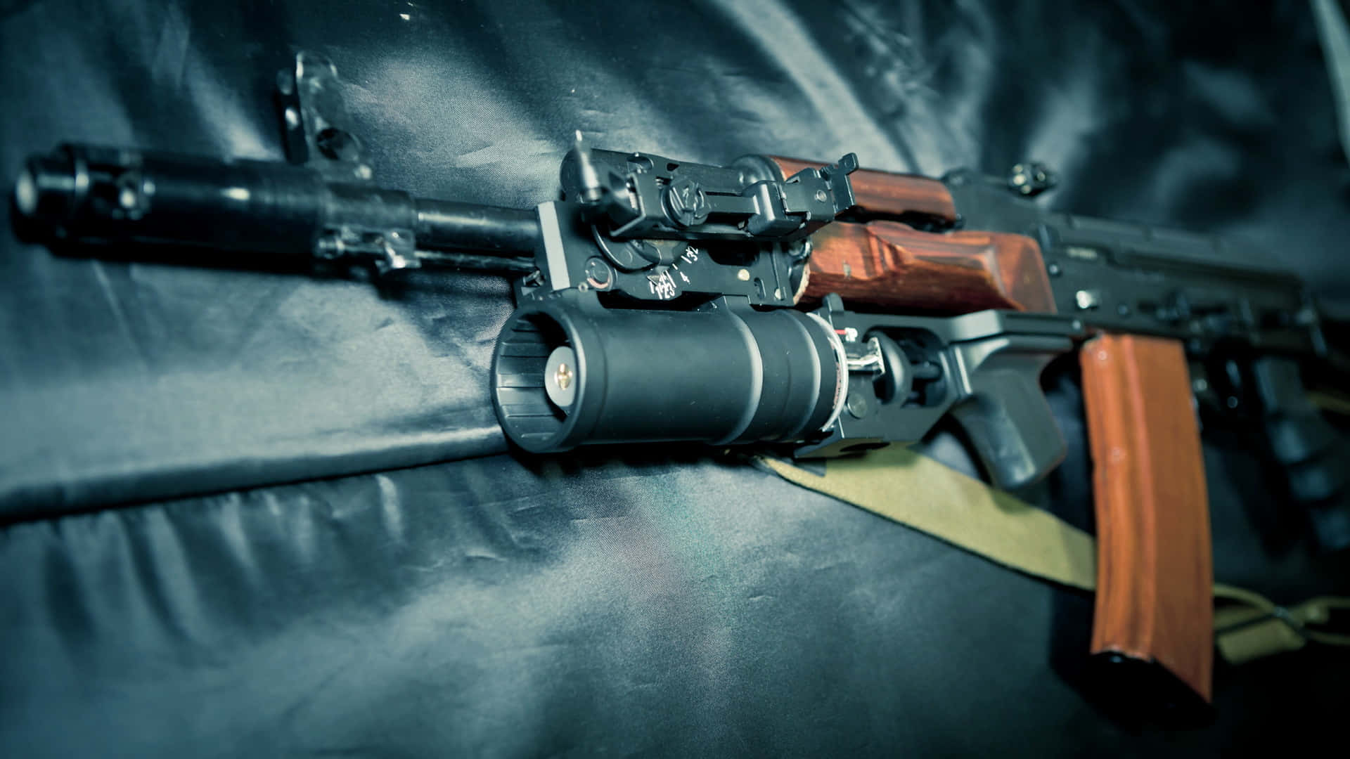 Rifle 桌布 壁紙 — 一把黑色突擊步槍，配有木製握把和安裝式瞄準鏡，在戲劇性燈光下放置在深色皮革軟墊上。