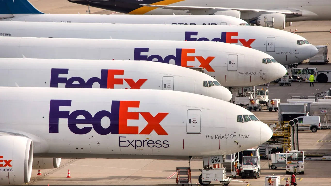 聯邦快遞 桌布 壁紙 — 一排FedEx Express貨機停放在機場停機坪，附近有地面服務車輛。