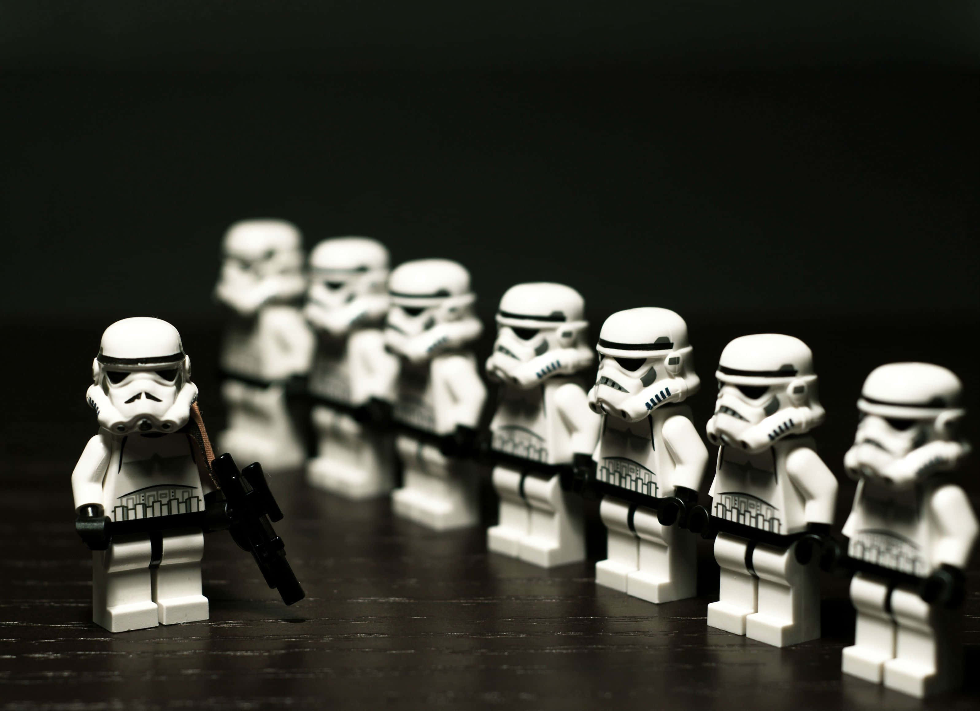 樂高 桌布 壁紙 — 一排LEGO風暴兵在黑暗背景前清晰對焦，景深較淺。