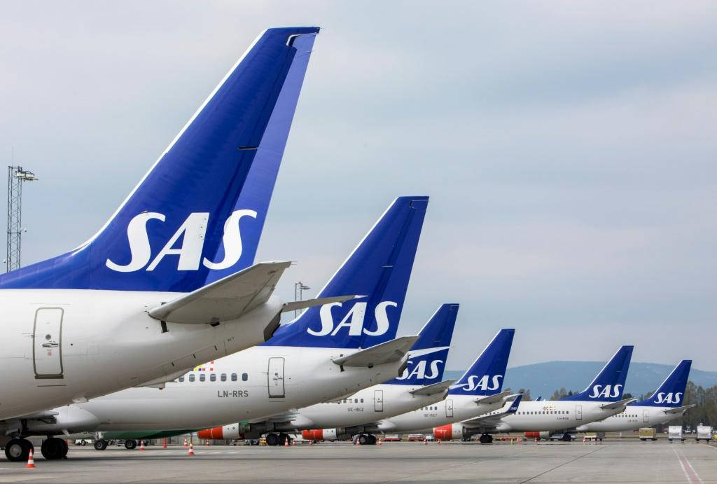 Airport 桌布 壁紙 — 一排SAS飛機停泊在機場停機坪上，天空多雲，背景有遠山。