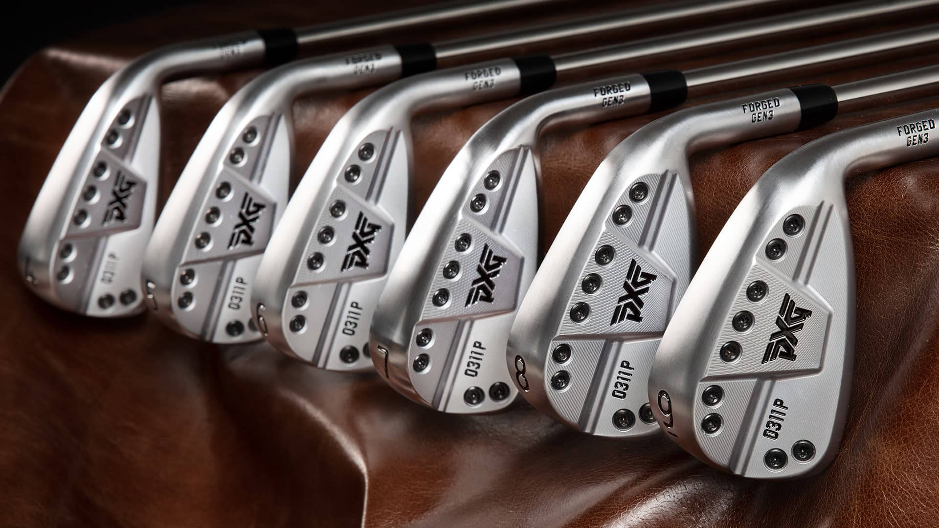 Golfing 桌布 壁紙 — 一排光滑的銀色PXG高爾夫鐵桿放在濃郁的棕色皮革上，精確的工程細節清晰可見。
