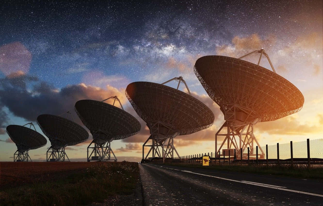Radio Telescope 桌布 壁紙 — 一排巨大的無線電望遠鏡在星光燦爛的暮色天空襯托下形成剪影，銀河在上方閃耀。