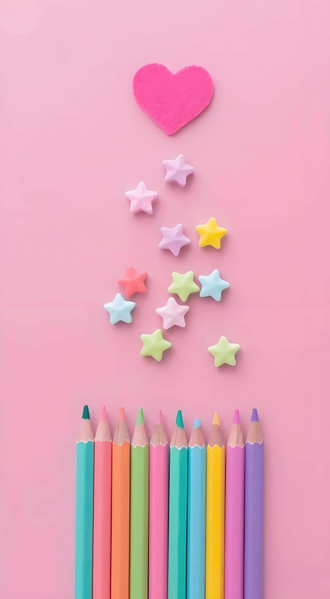 Pastel color pencil wallpaper 壁紙 — 一排彩色鉛筆在粉紅色背景上，上方有一個粉紅色愛心和散落的粉彩星星。