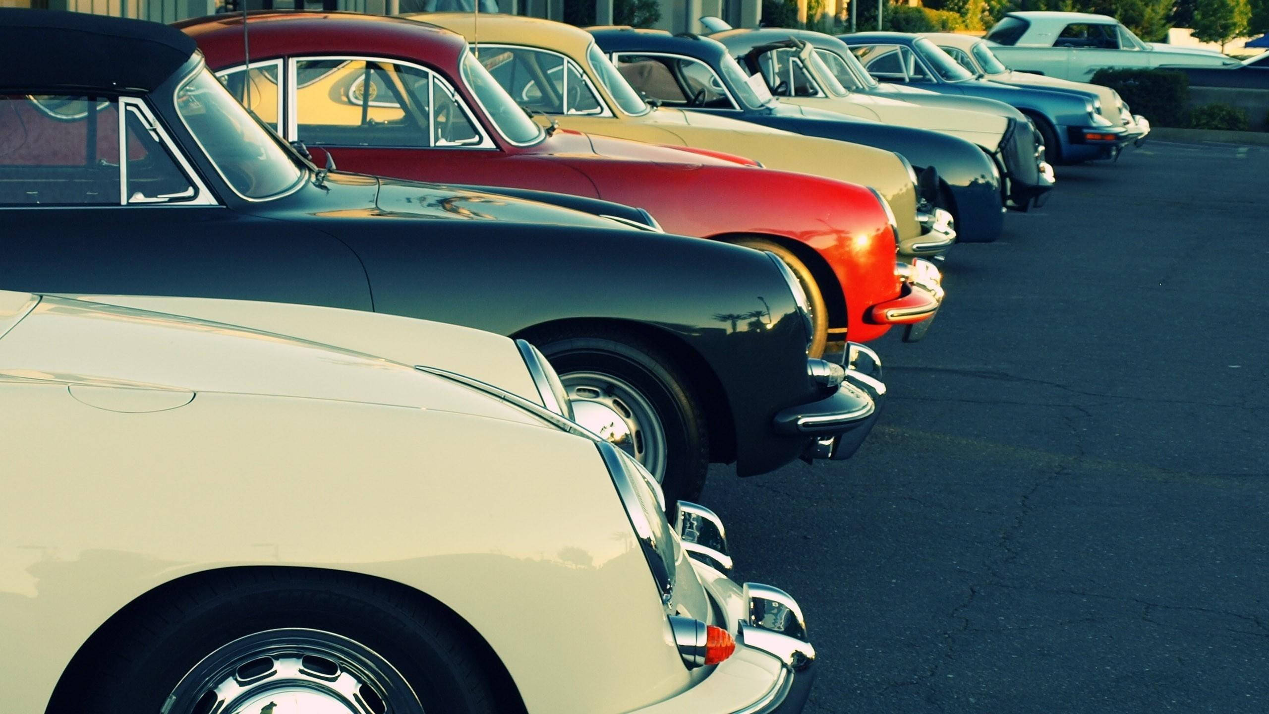 cars 桌布 壁紙 — 一排復古經典汽車停放在停車場，光亮的漆面反射著溫暖的陽光。