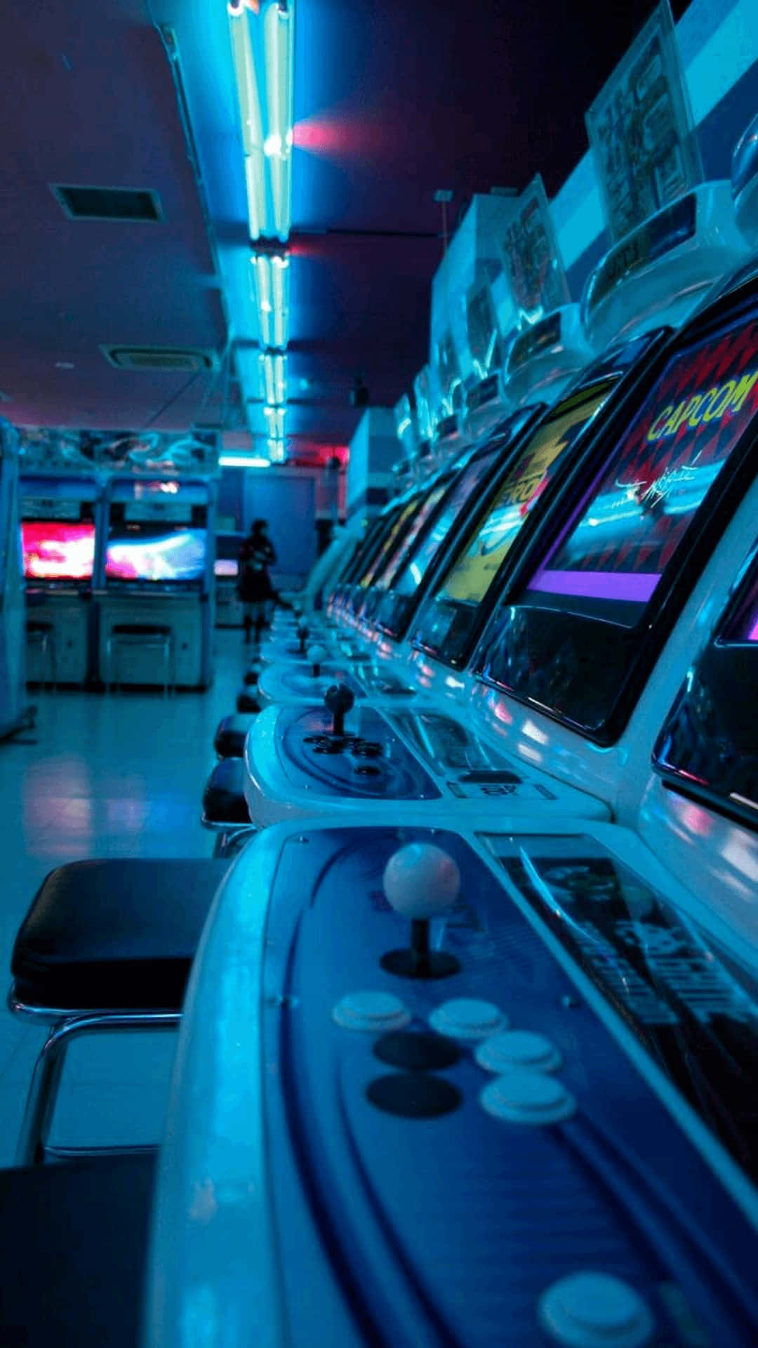 Arcade Aesthetic 桌布 壁紙 — 一排復古街機在霓虹燈下發光，位於懷舊遊戲廳內。