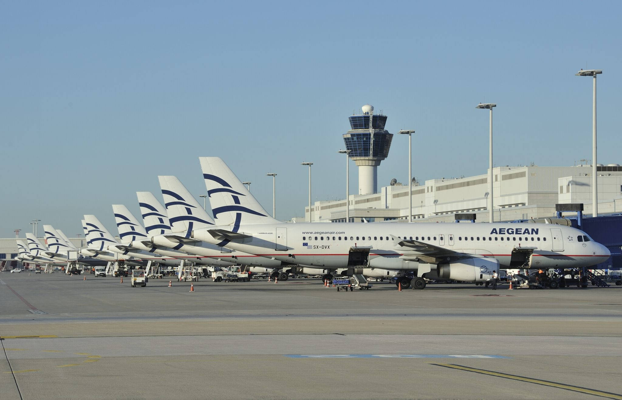 Airport 桌布 壁紙 — 一排愛琴海航空的飛機停在機場停機坪上，背景是晴朗的藍天和一座控制塔。
