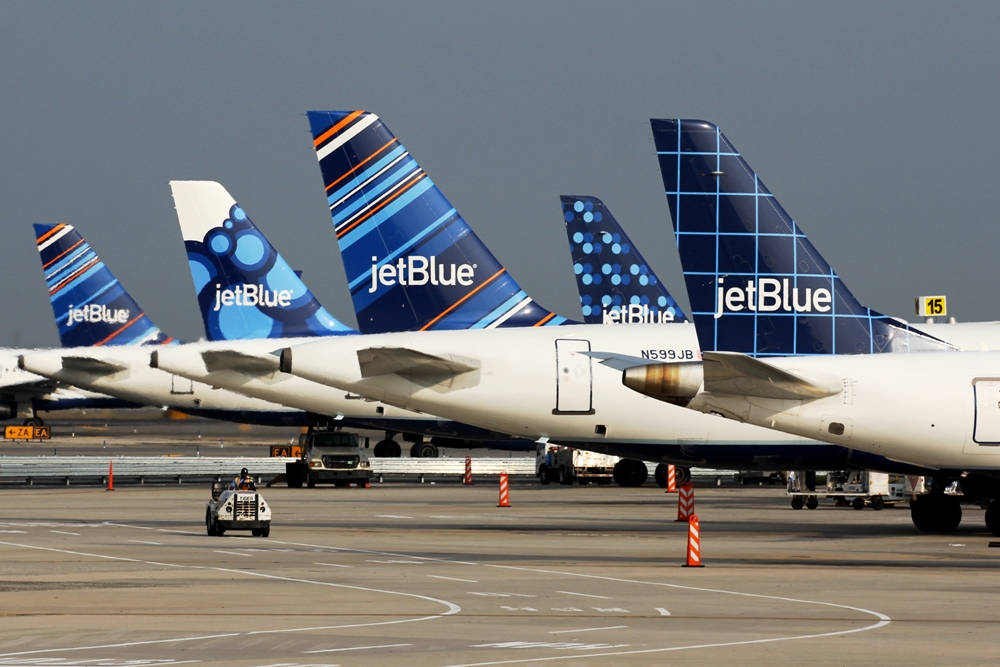 飛機 桌布 壁紙 — 一排捷藍航空飛機停泊在機場閘口，色彩繽紛的機尾朝前，天空多雲。