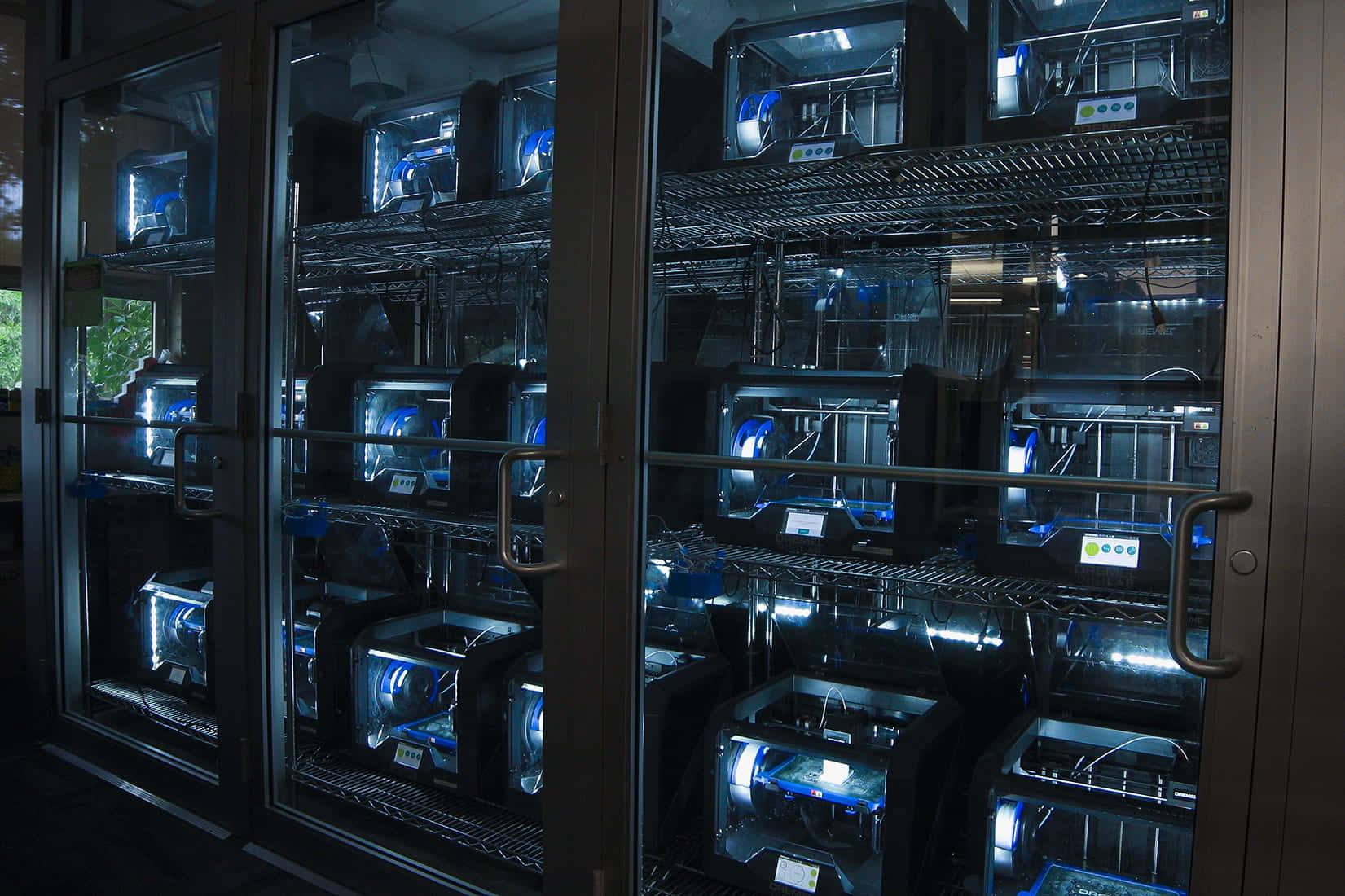 3d Printer 桌布 壁紙 — 一排排3D列印機在昏暗房間的玻璃櫃內發出藍光。