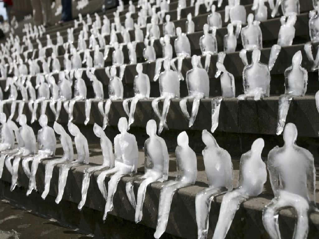 Ice Sculpture 桌布 壁紙 — 一排排冰凍的人形雕像靜靜地坐在石頭看台上，在寒冷日光下被清澈的冰層包裹。
