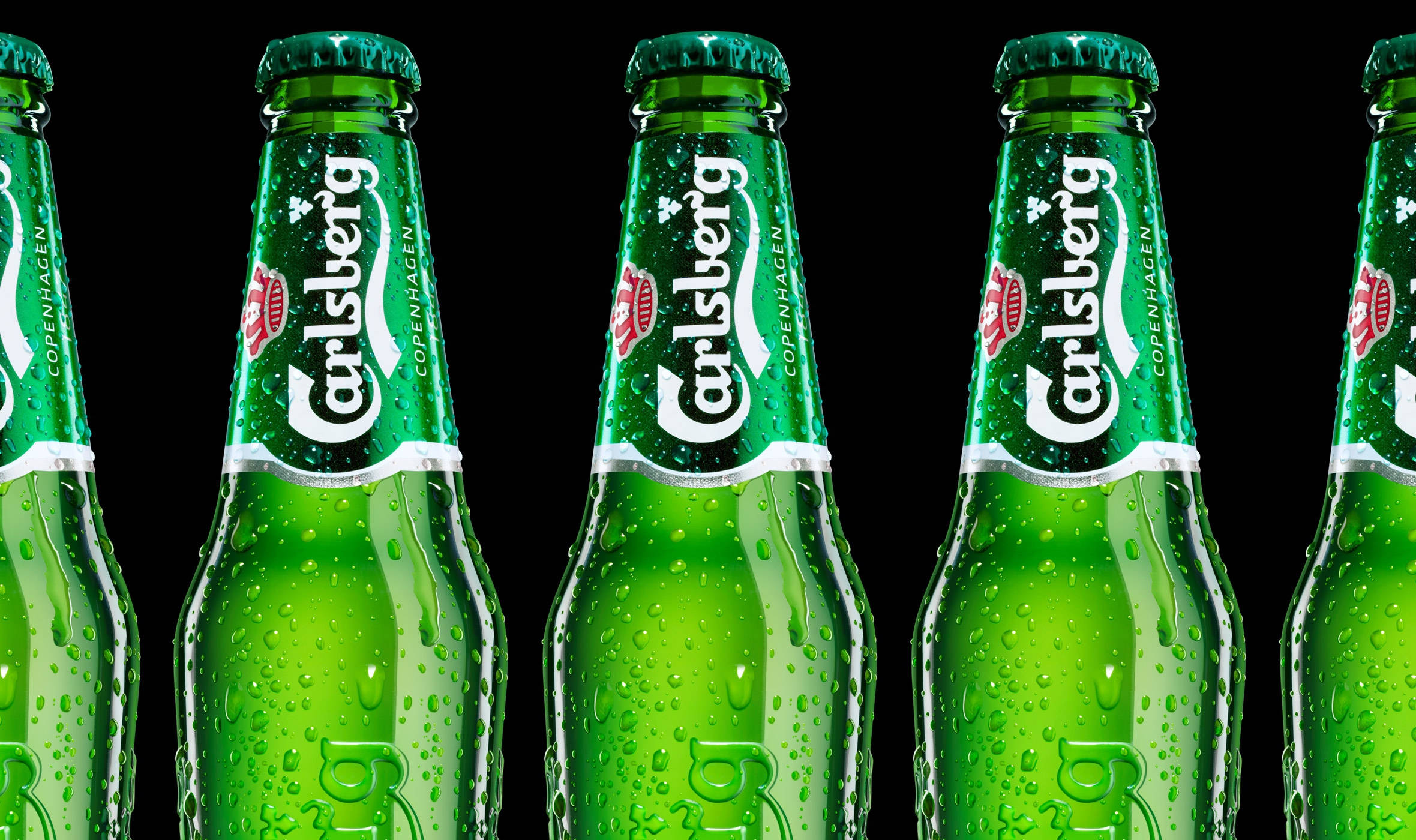 Beer 桌布 壁紙 — 一排排冰涼的綠色嘉士伯啤酒瓶在純黑色背景上閃爍著冷凝水珠。