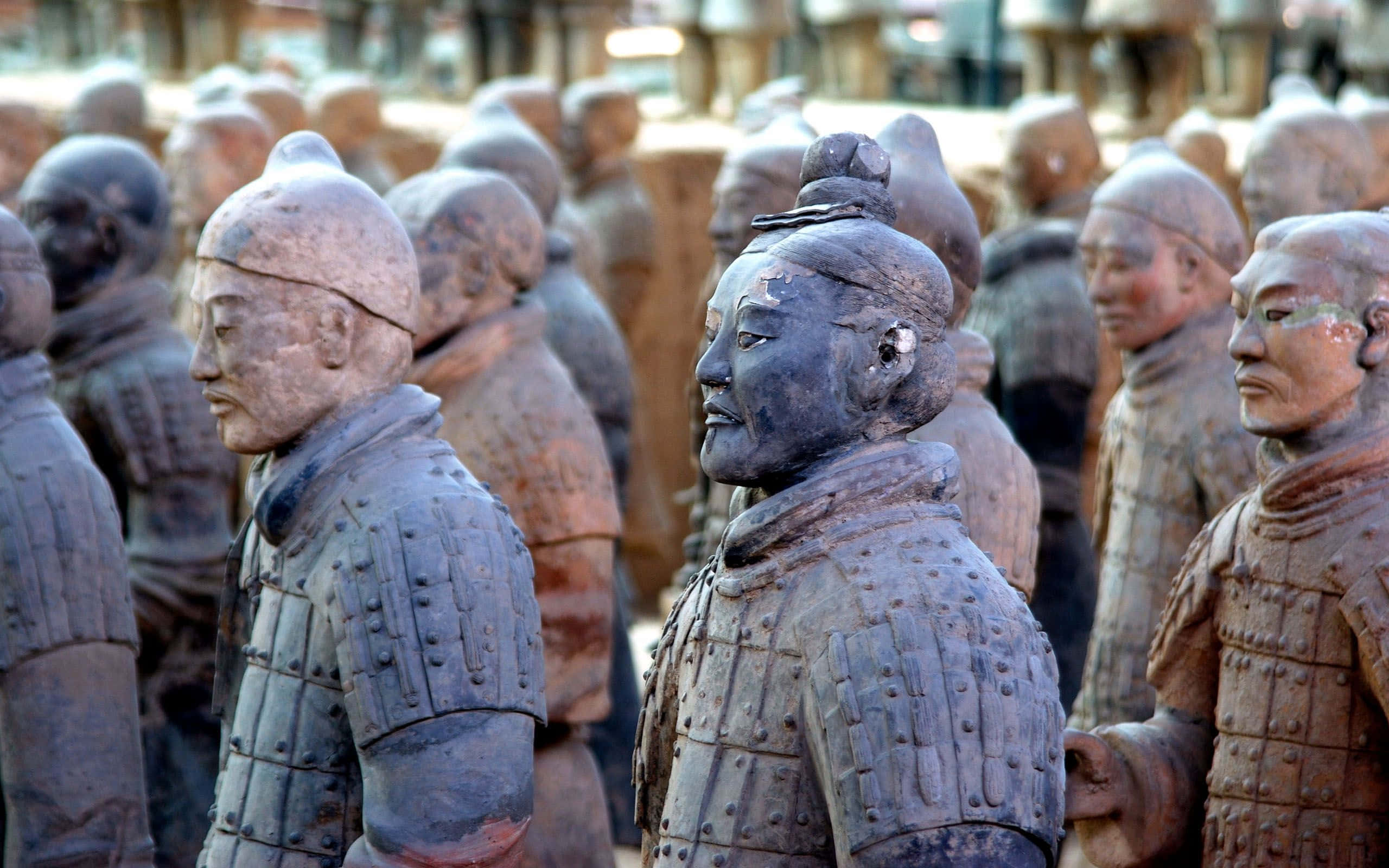Museum 桌布 壁紙 — 一排排古老的兵馬俑在柔和日光下整齊排列，細節豐富的盔甲和風化的表情顯得莊嚴肅穆。