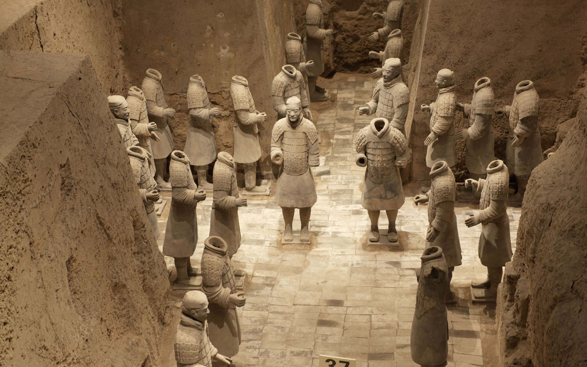Museum 桌布 壁紙 — 一排排古老的兵馬俑在泥土色的發掘室內列隊站立。