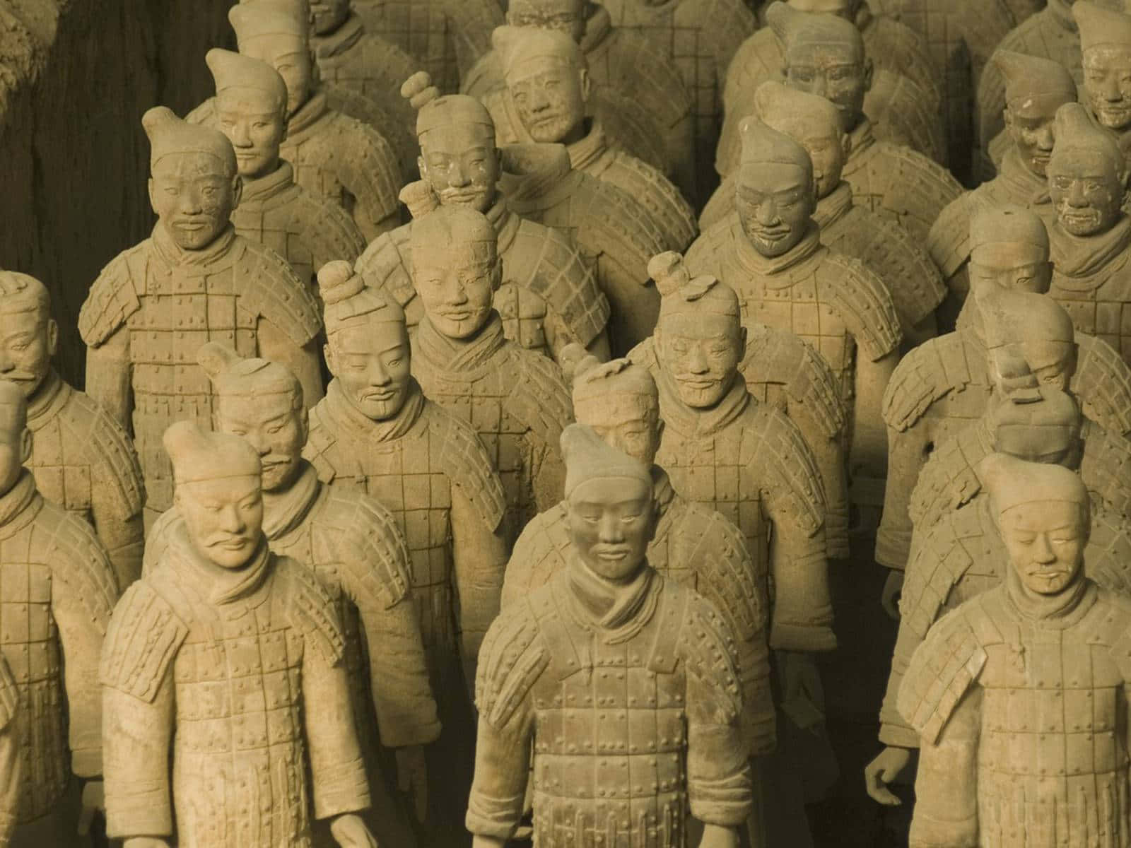 Museum 桌布 壁紙 — 一排排古老的兵馬俑在溫暖的燈光下莊嚴列隊，展現出精細的盔甲和獨特的面部表情。