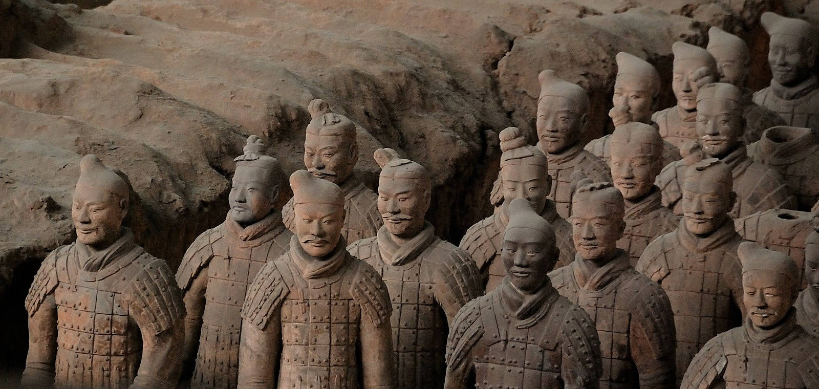 Xian 桌布 壁紙 — 一排排古老的兵馬俑莊嚴地矗立在發掘坑中，帶有泥土色調和風化細節。