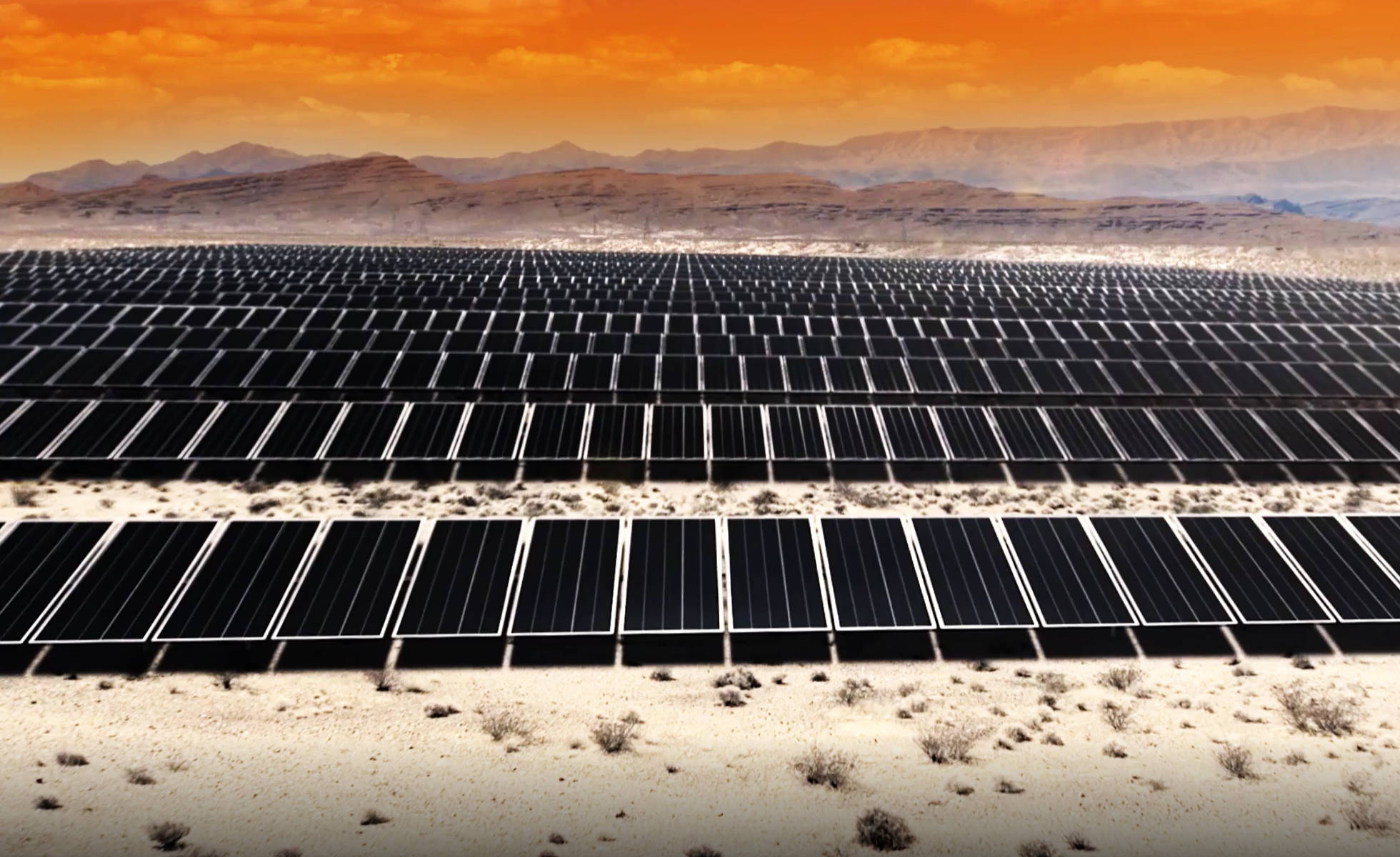 Solar Panel 桌布 壁紙 — 一排排太陽能板在火紅橙色的日落天空下延伸穿過沙漠。