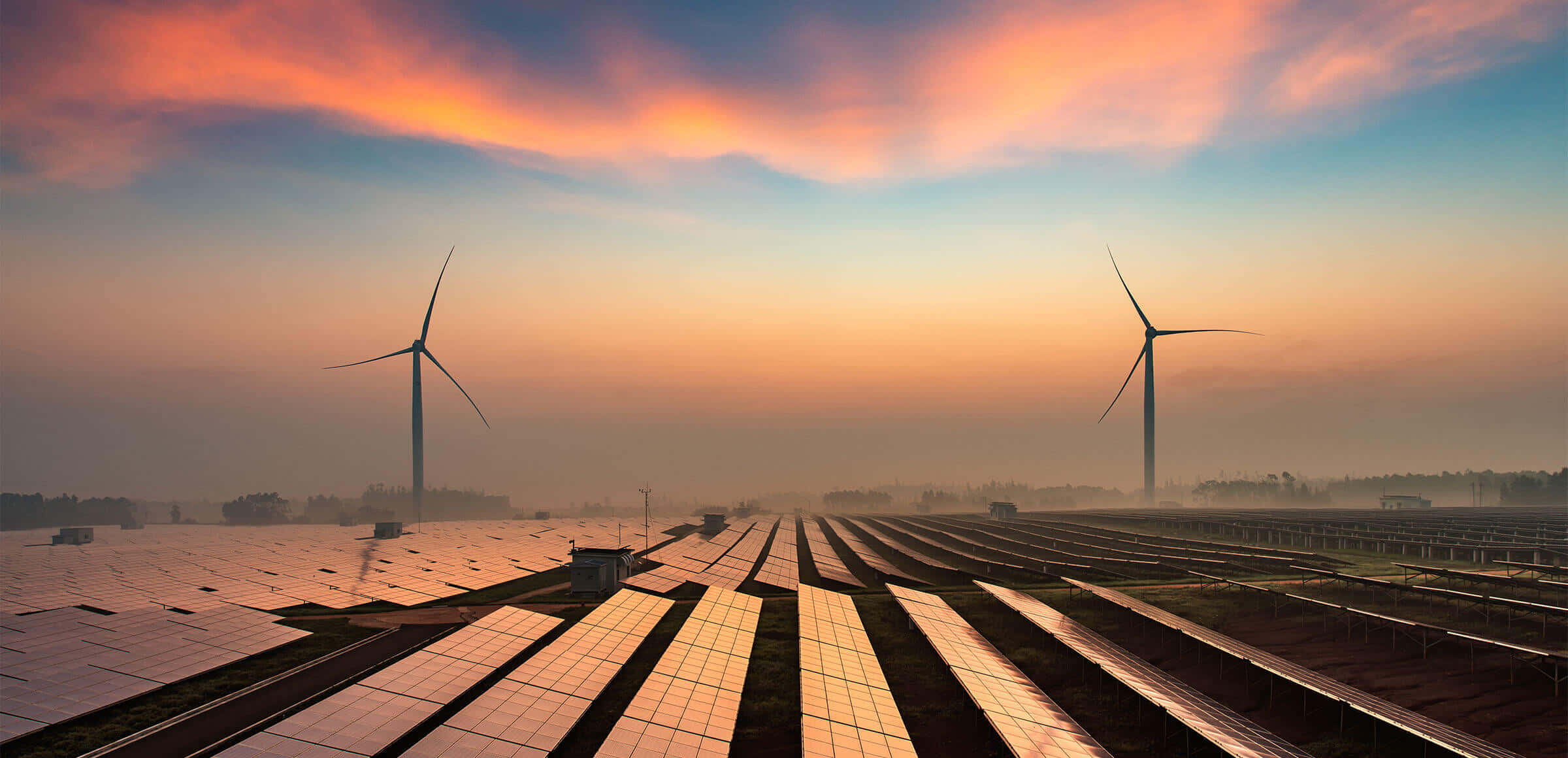 Energy 桌布 壁紙 — 一排排太陽能板在火紅的日落天空下向風力渦輪機延伸。