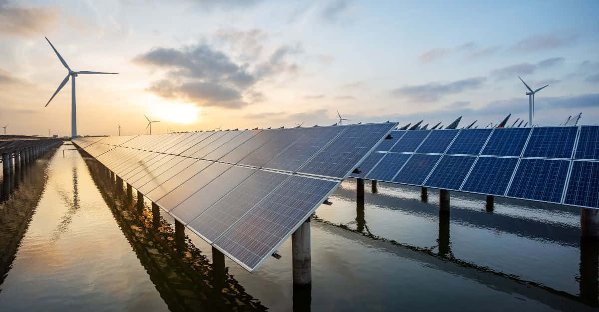 Renewable Energy 桌布 壁紙 — 一排排太陽能板漂浮在水面上，風力渦輪機在金色夕陽天空下高高聳立。