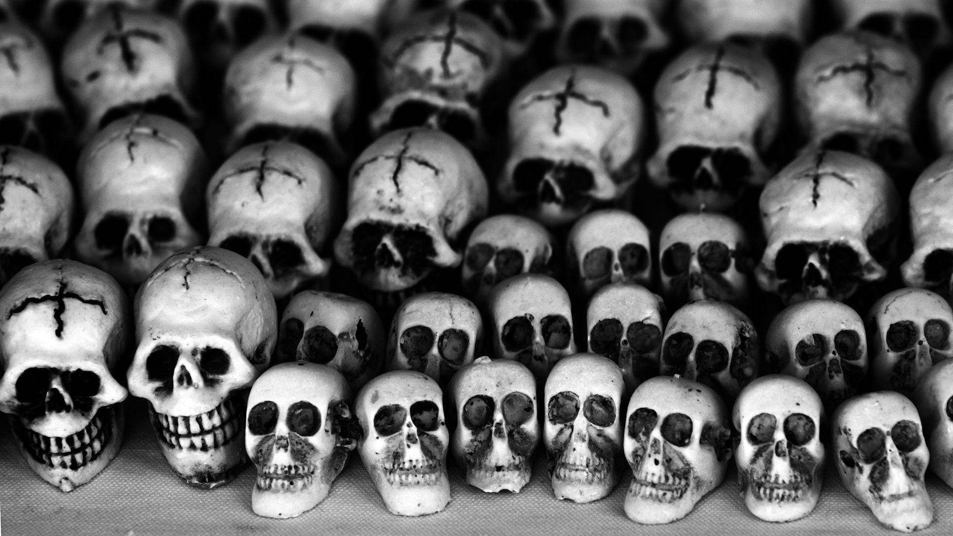 dead 桌布 壁紙 — 一排排帶有十字標記的人類頭骨，以陰鬱的黑白構圖排列。