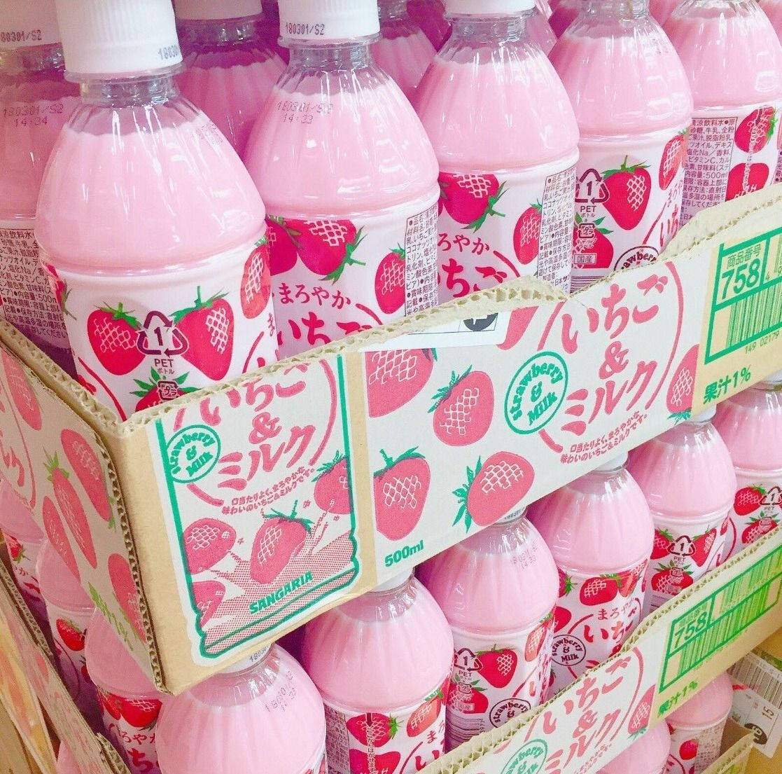 Strawberry Milk 桌布 壁紙 — 一排排帶有日本標籤的粉紅色草莓牛奶瓶整齊地堆疊在紙板展示盒中。