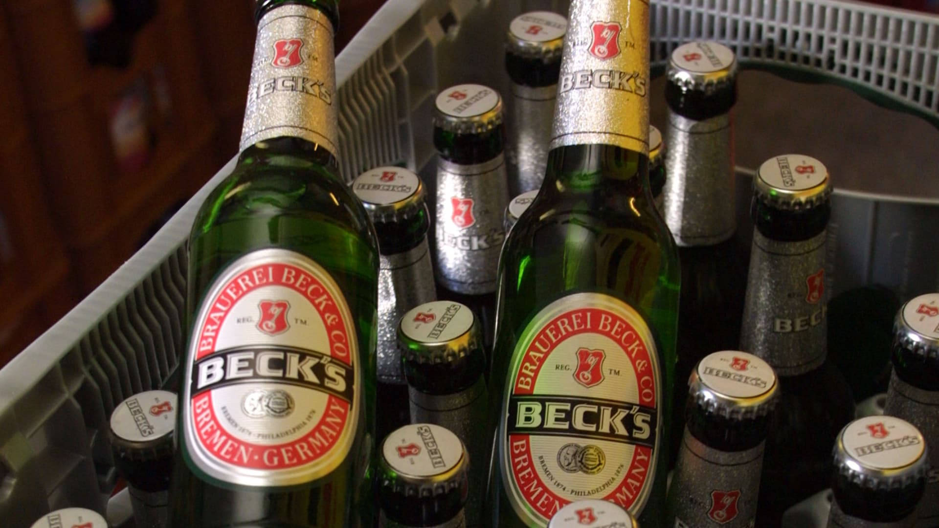 Beer 桌布 壁紙 — 一排排帶有銀色瓶蓋的貝克啤酒瓶放在金屬冷卻托盤中冷藏。