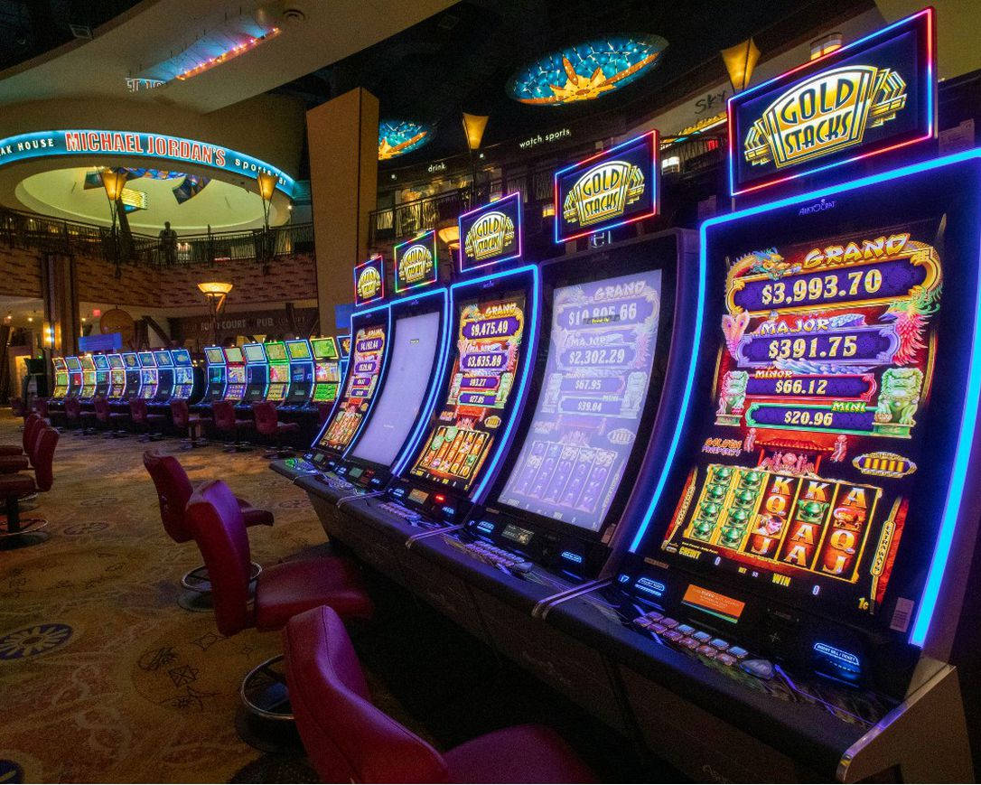 arcade 桌布 壁紙 — 一排排明亮照明的老虎機在帶有霓虹燈標誌和紅色椅子的賭場中，在溫暖的環境燈光下閃耀。